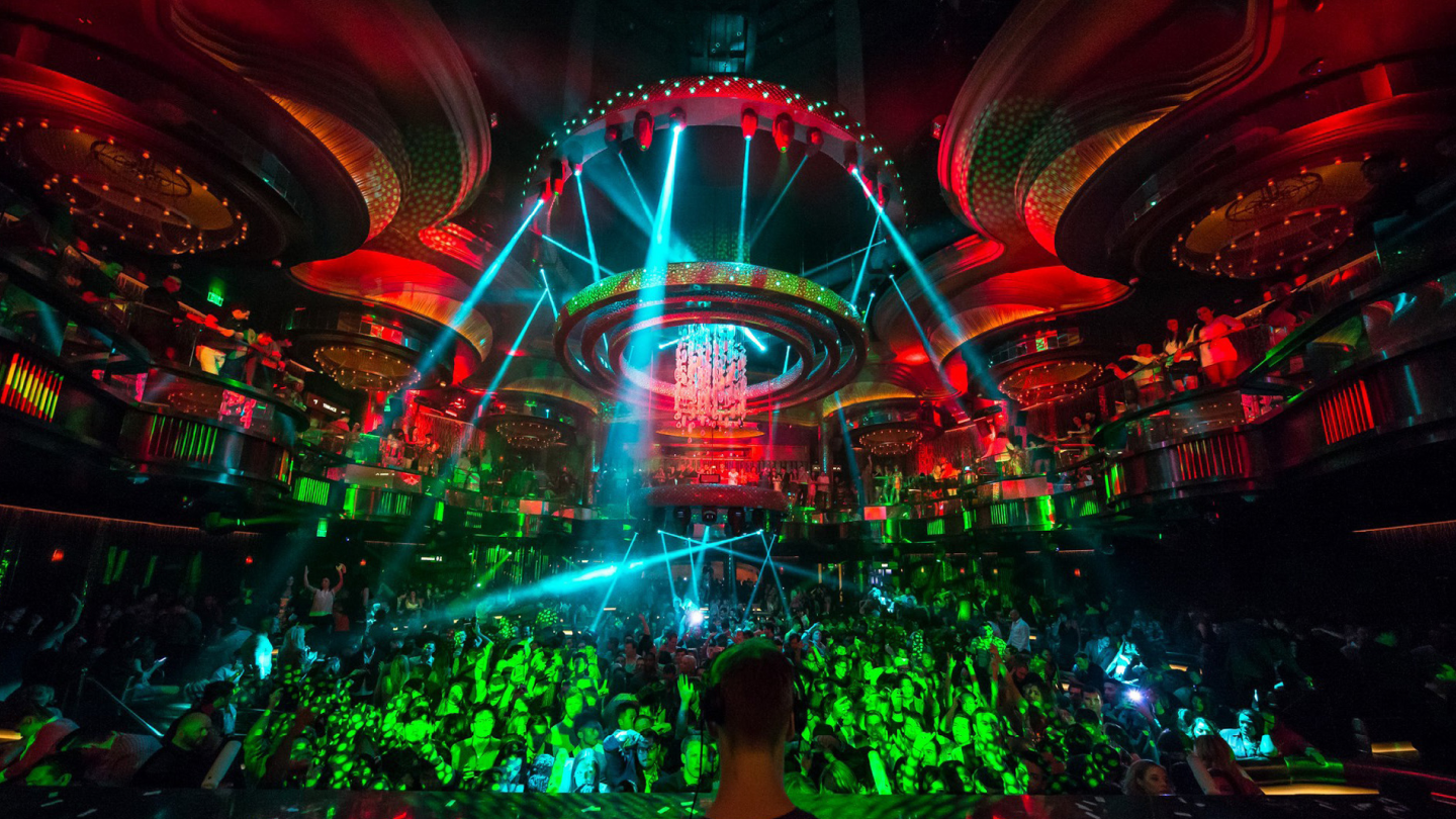 club full of people dancing with light show happening