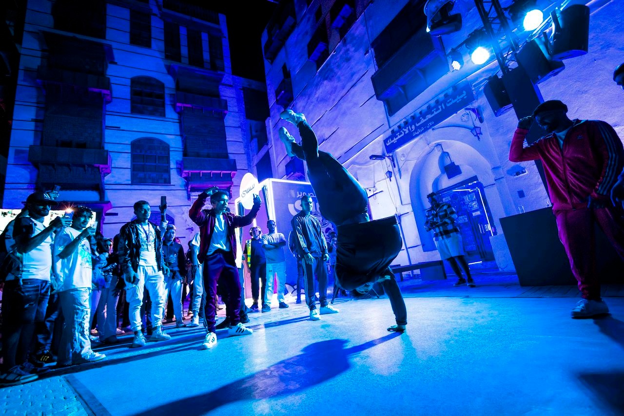 Dancer spinning on their hand with a crowd watching