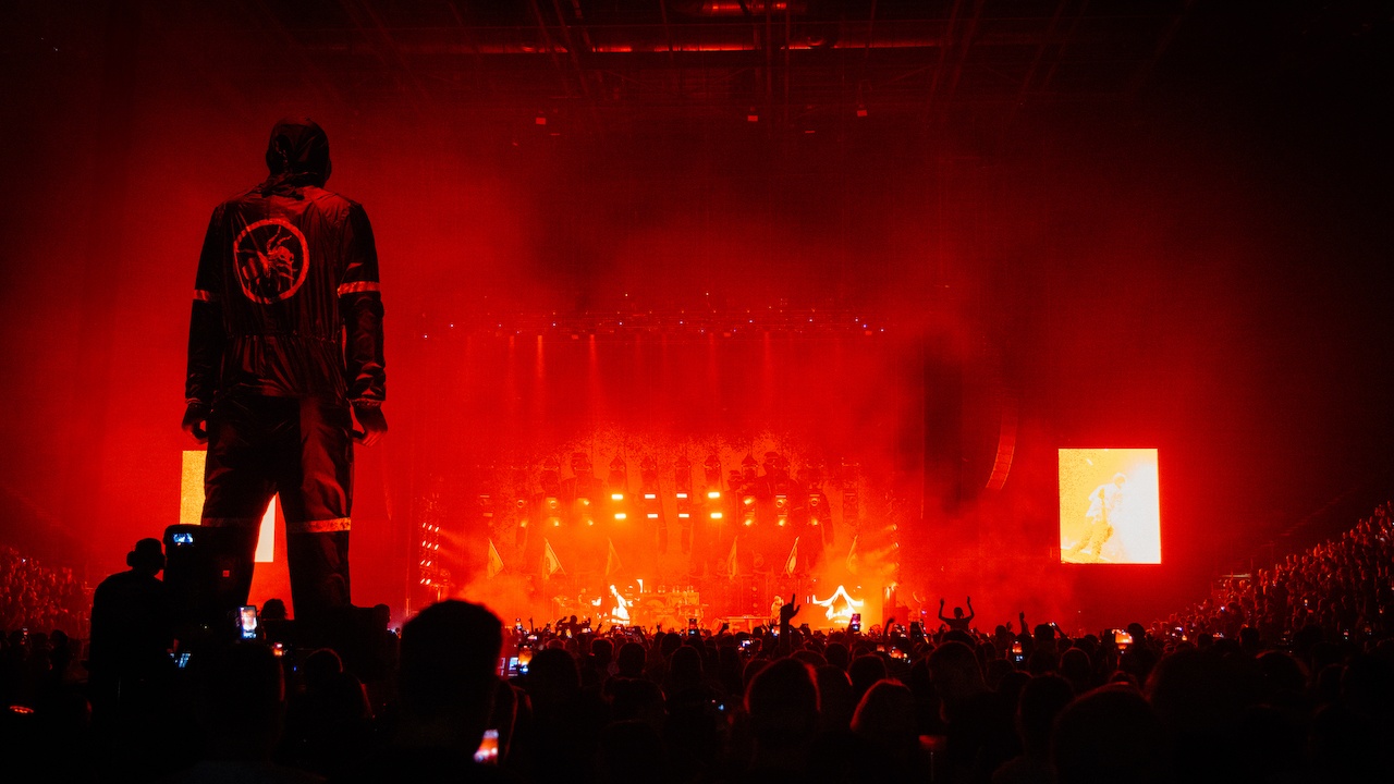 Huge scenic mani n overalls stood over thousands of cheering fans watching the Prodigy on stage in red lighting