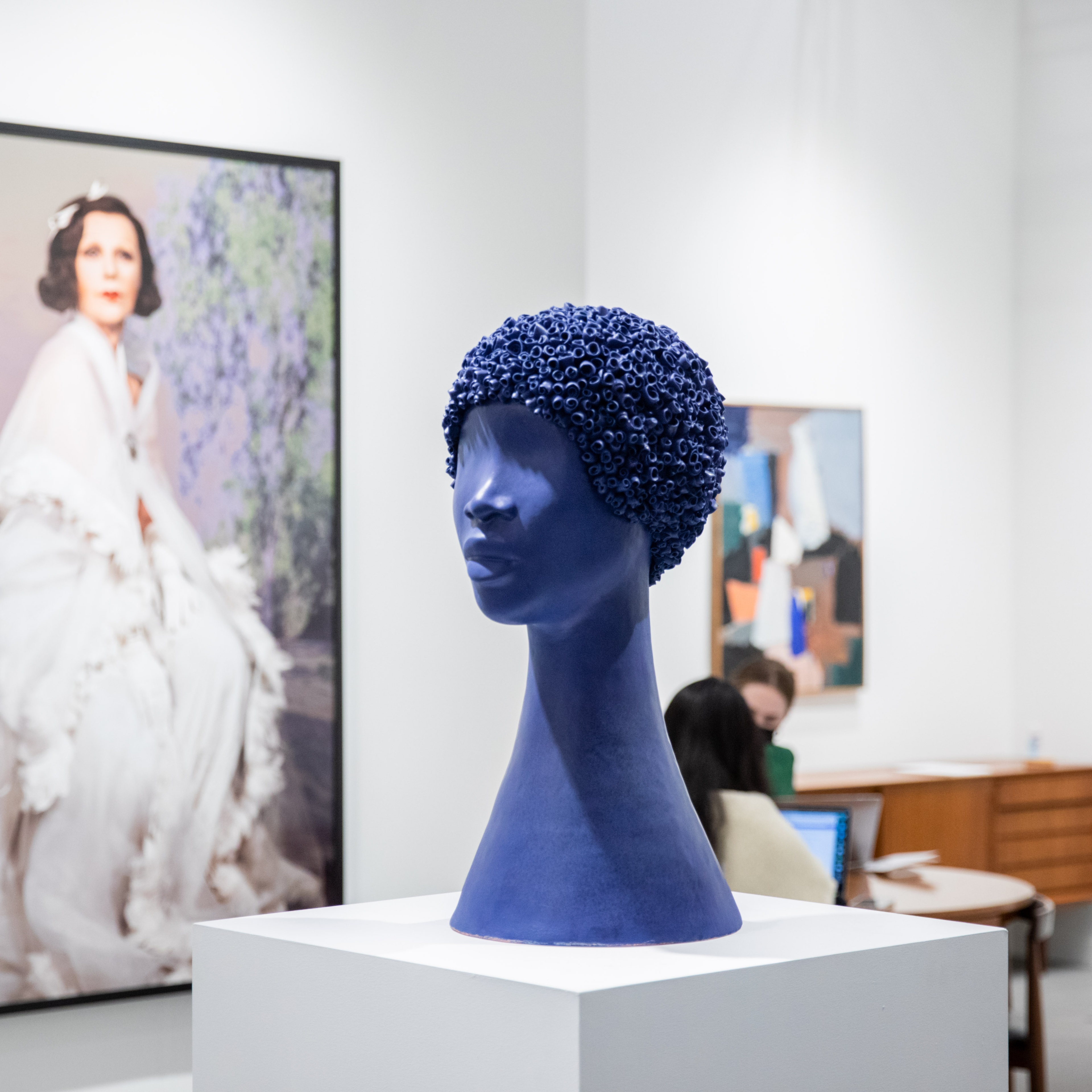 Blue mannequin head in front of a painting