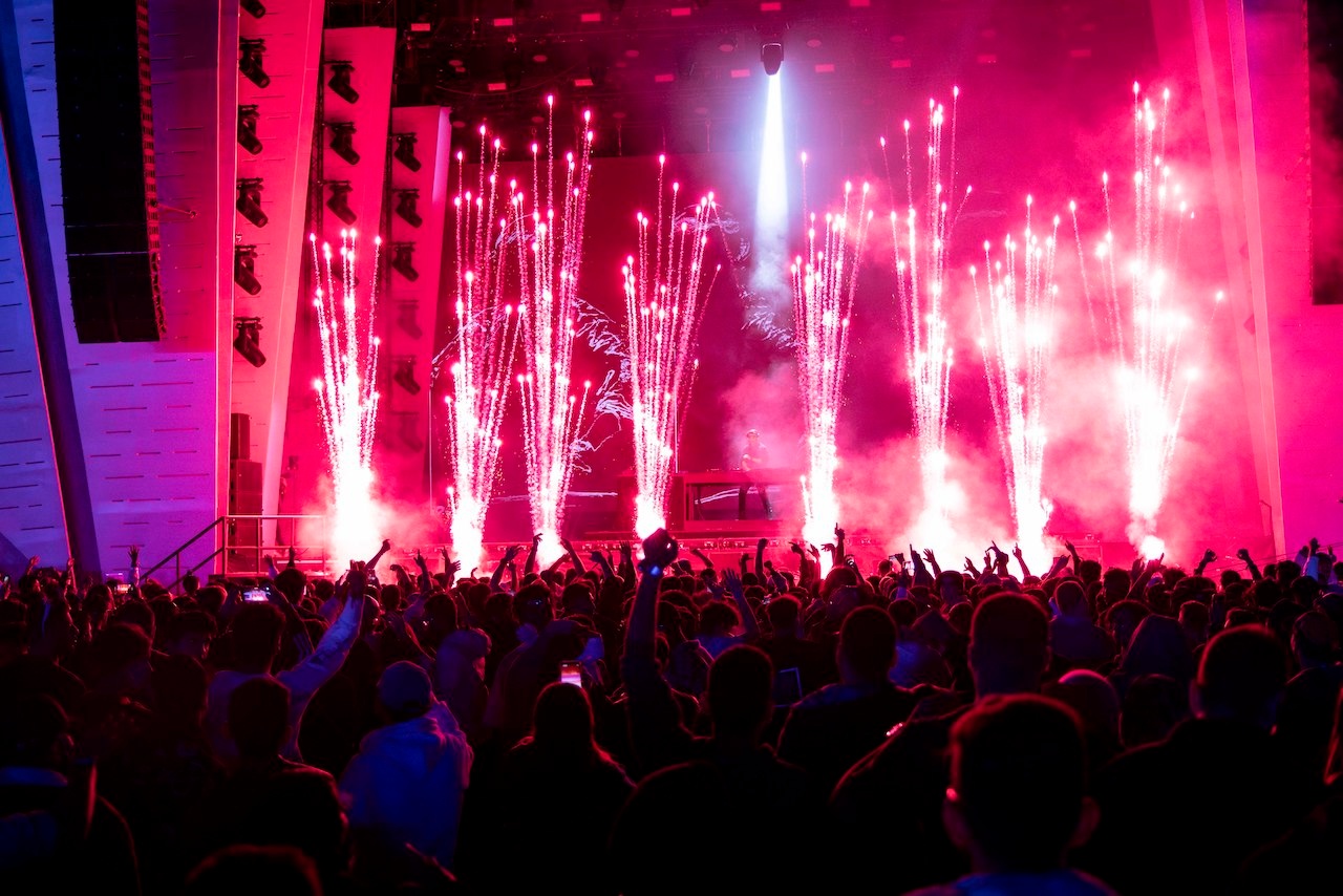 Stage with pink pyrotechnics in front of cheering crowd