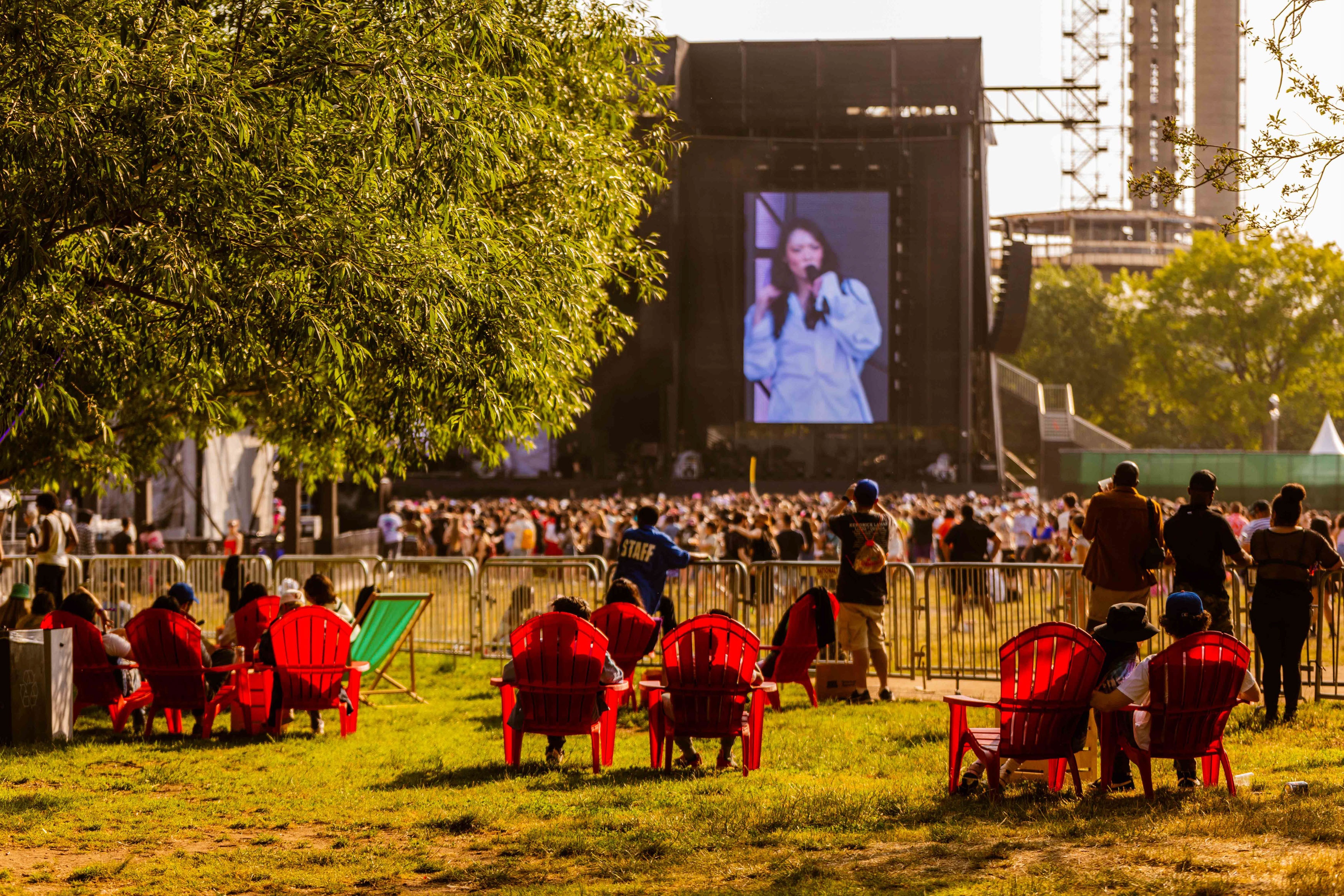 Founders Entertainment The Governors Ball people seating in red plastic chairs facing a big screen on stage showcasing a female sing