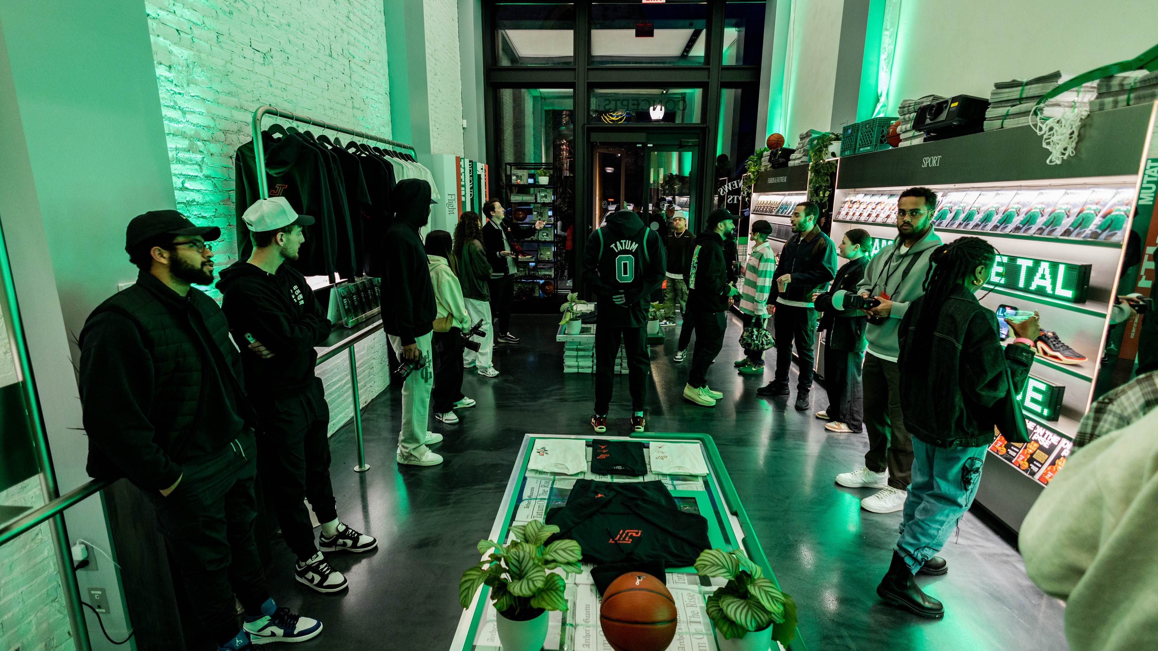 people gathered in green lit brand experience looking at merchandise in industrial setting
