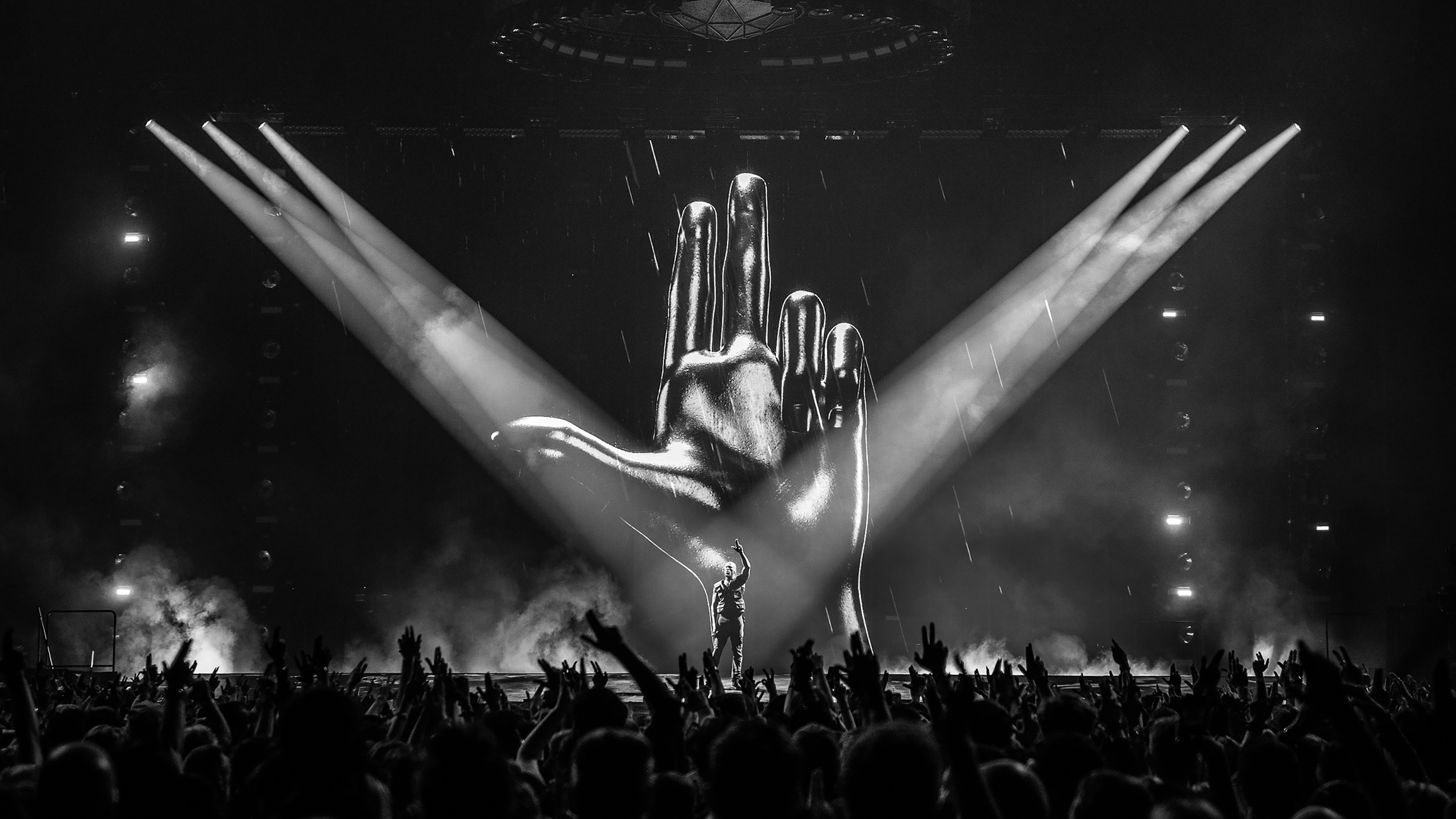 Rapper Stormzy performing on stage with cheering crowd and spotlights in front of a huge LED wall with chrome hand