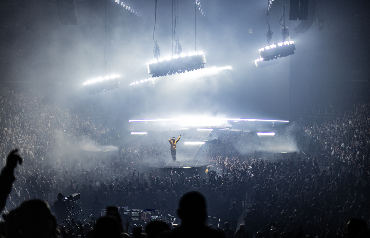 Post Malone in yellow shirt on stage with white lighting