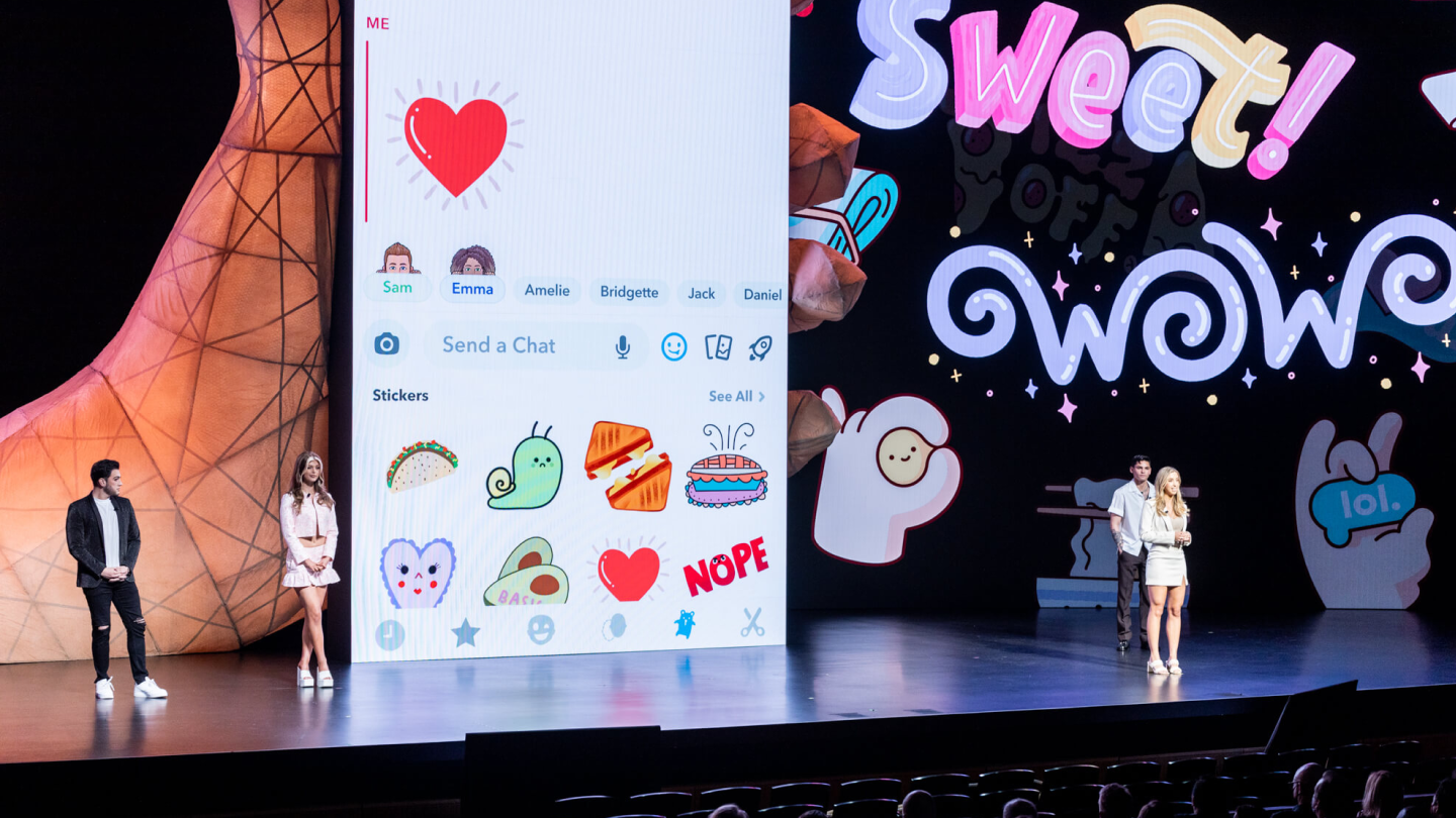 4 people on stage with 15+ foot tall phone screen on stage