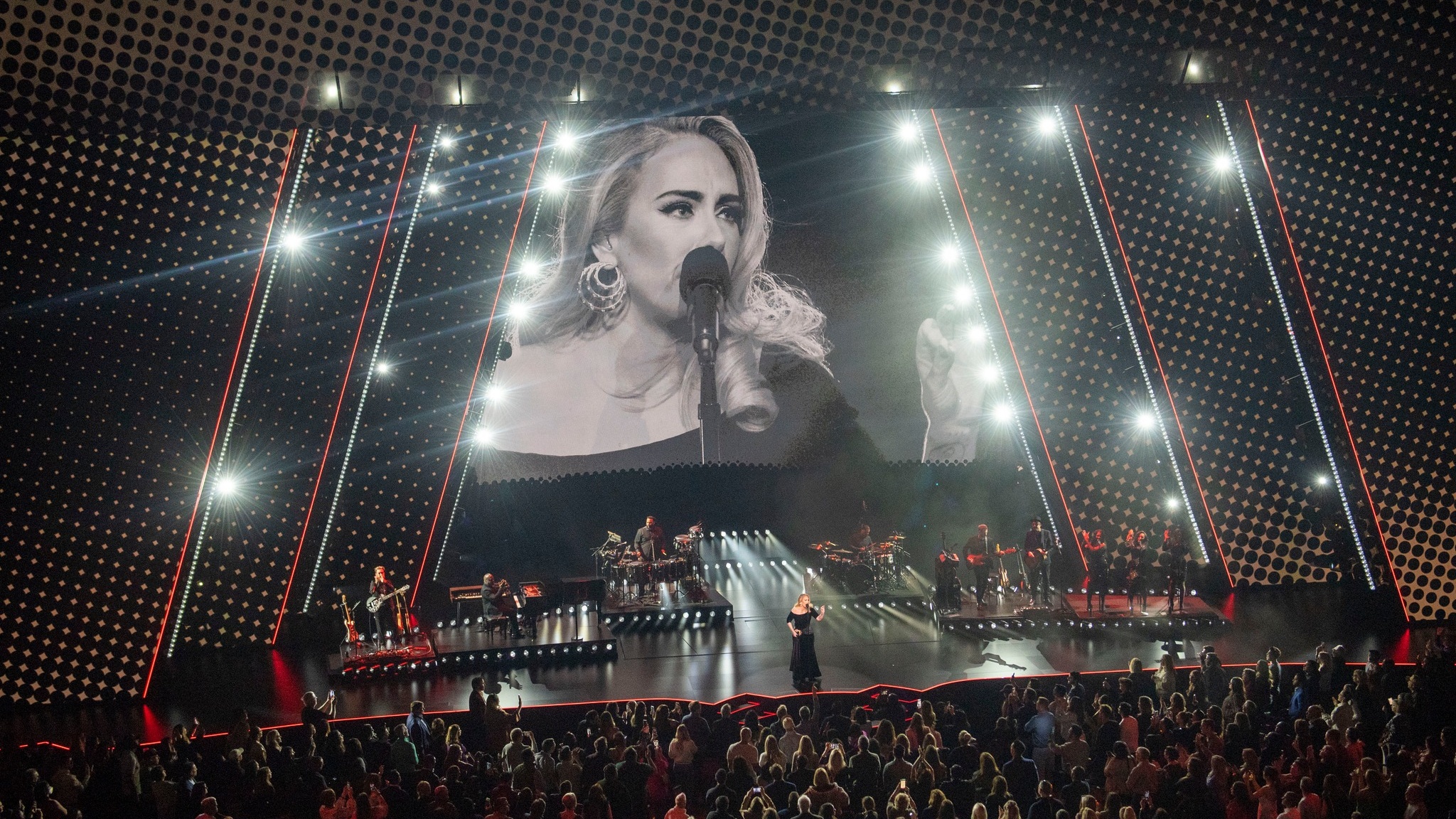 Singer Adele performing on stage in front of full band and a live video of her on huge LED Screen