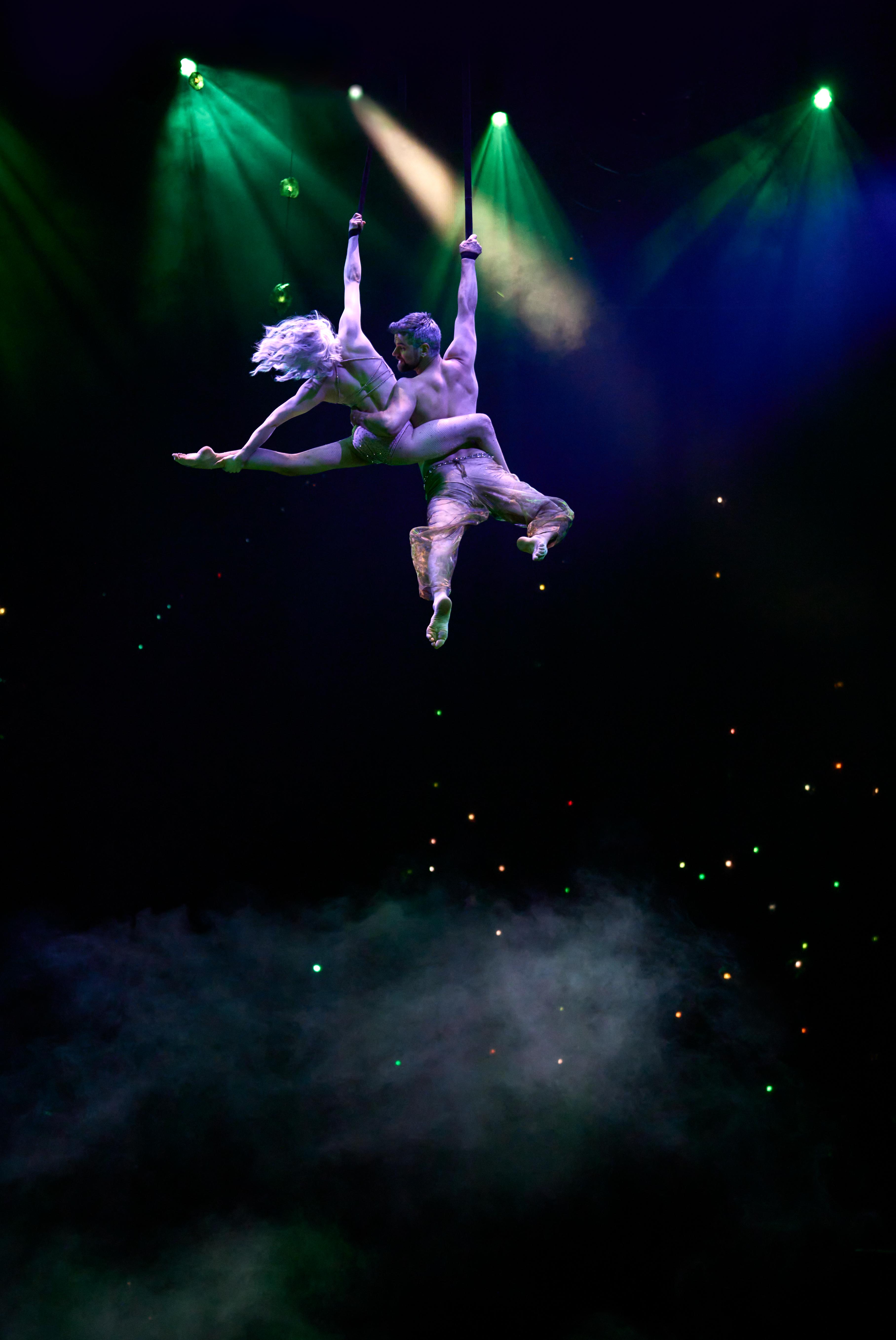 Awakening performers flying above stage in white costume
