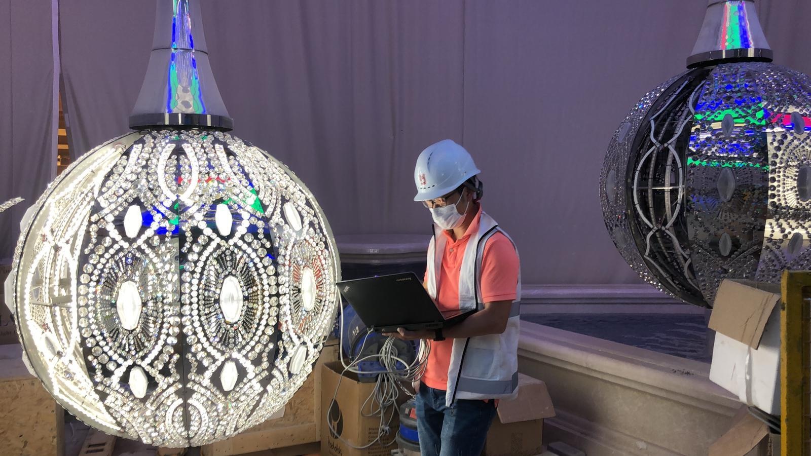 Architectural kinetic Lous flower sculpture installed in centre of grand lobby with chandeliers and light displays