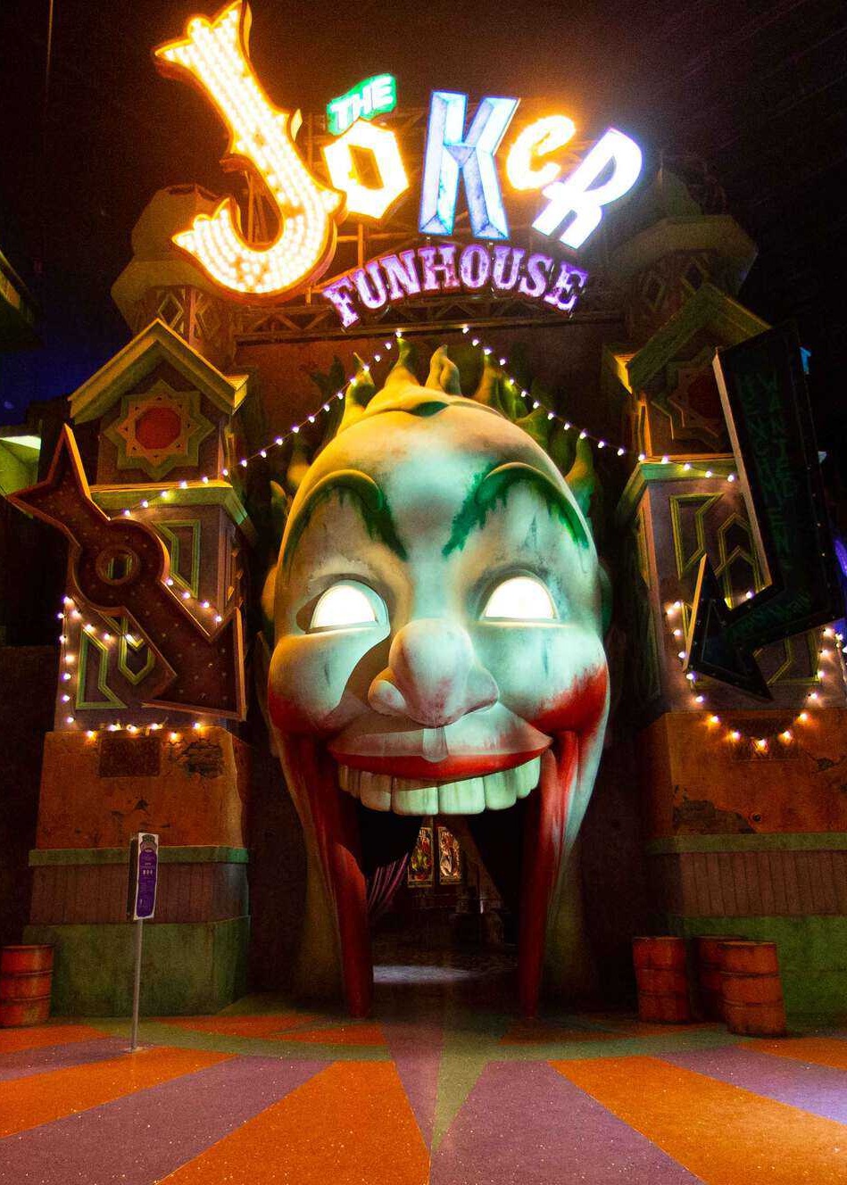 Lit up sign saying "The Joker Funhouse" above a large clown face with an open mouth