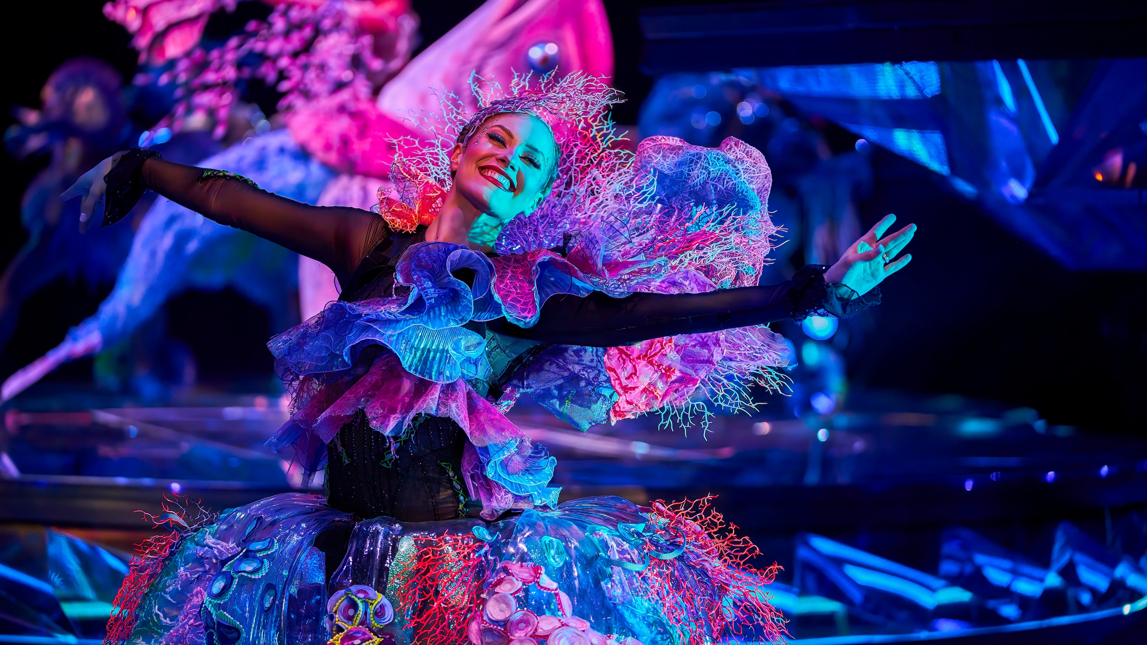 Awakening performer smiling on stage in brightly colored costume