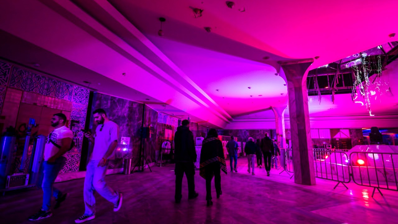 People walking through pink lit industrial space