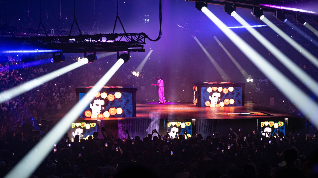 Rapper Drake performer on stage lit with green lighting looking up at green space ship with crowd