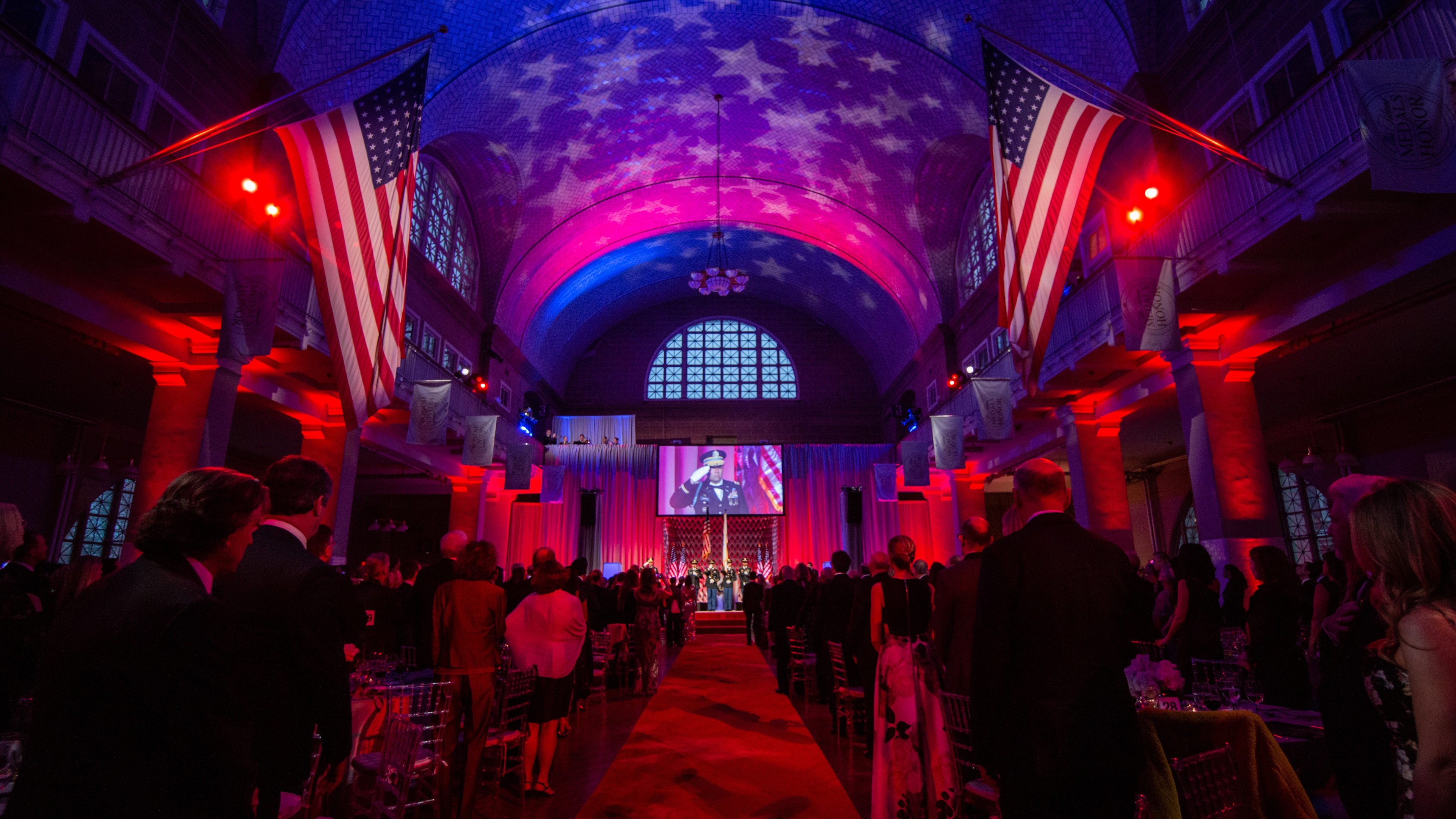 People gathered for ceremony with red lights and american flags and stars