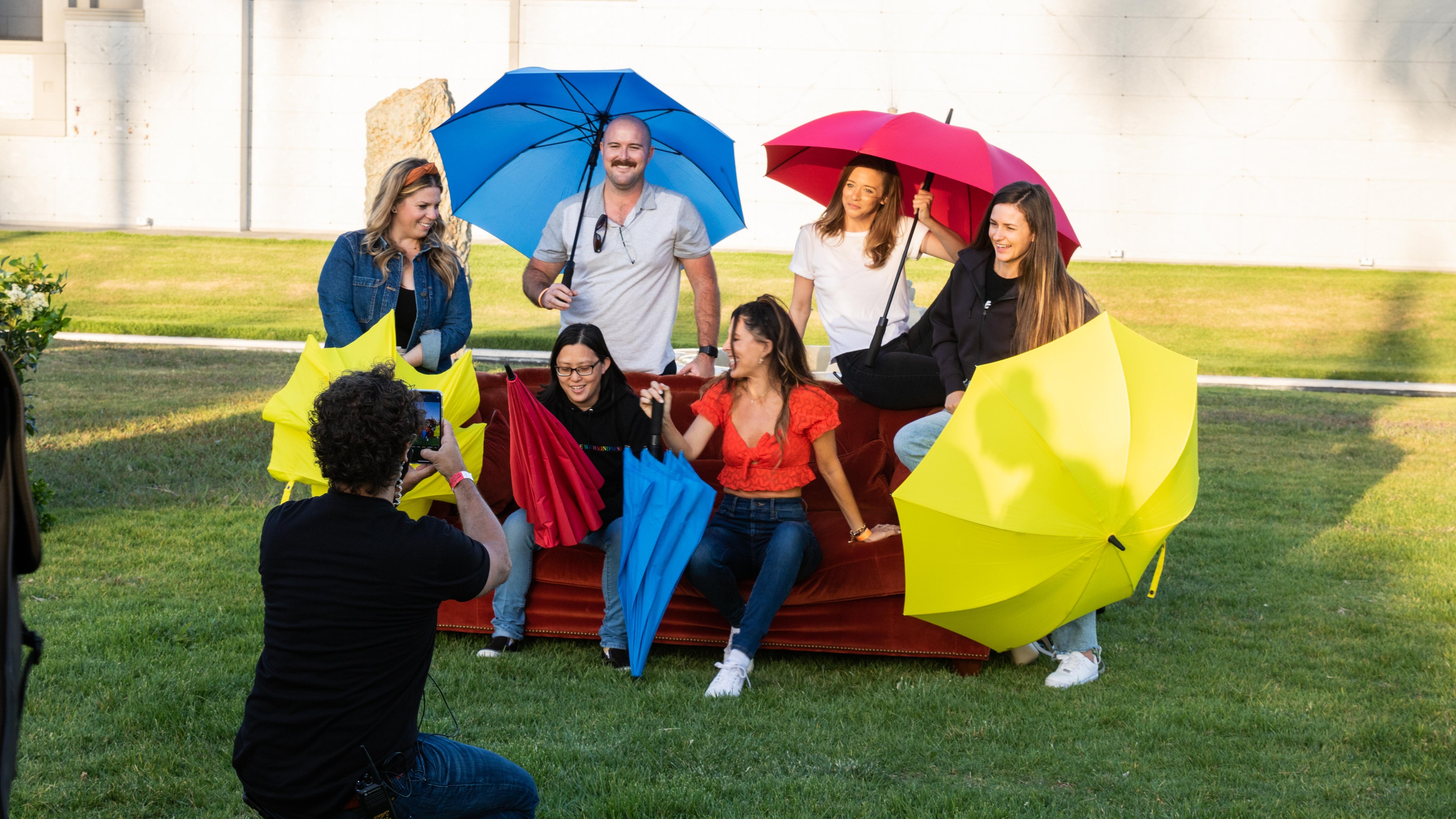 people sat on the friends sofa with umbrellas having their photo taken