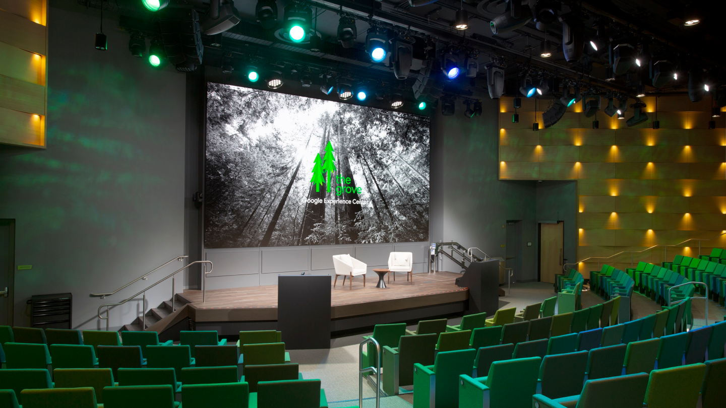 indoor amphitheater with stadium seating and a small stage with a projection screen