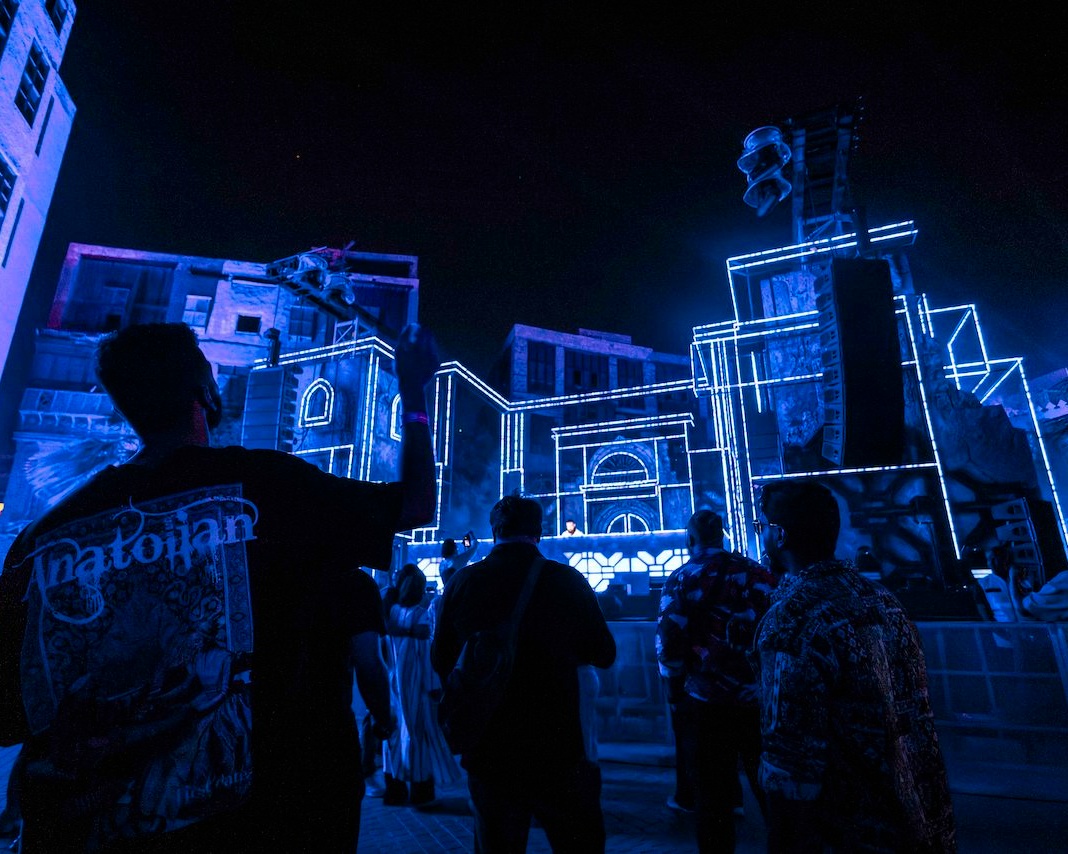 Outdoor projection outlining buildings with crowd in foreground