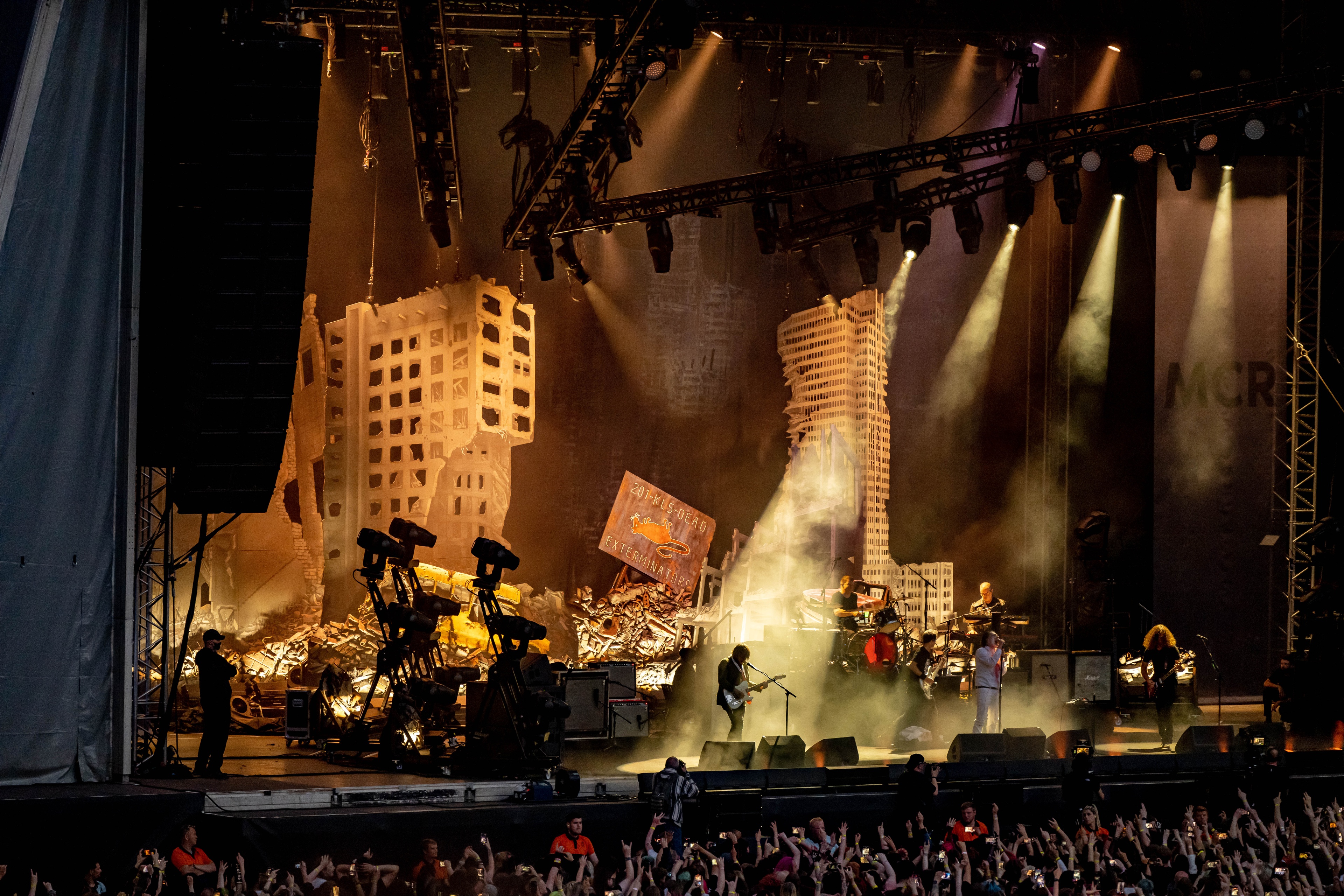 view from the crowd of My Chemical Romance performing at the Foundations Tour, in a post-apocalyptic rubble backdrop