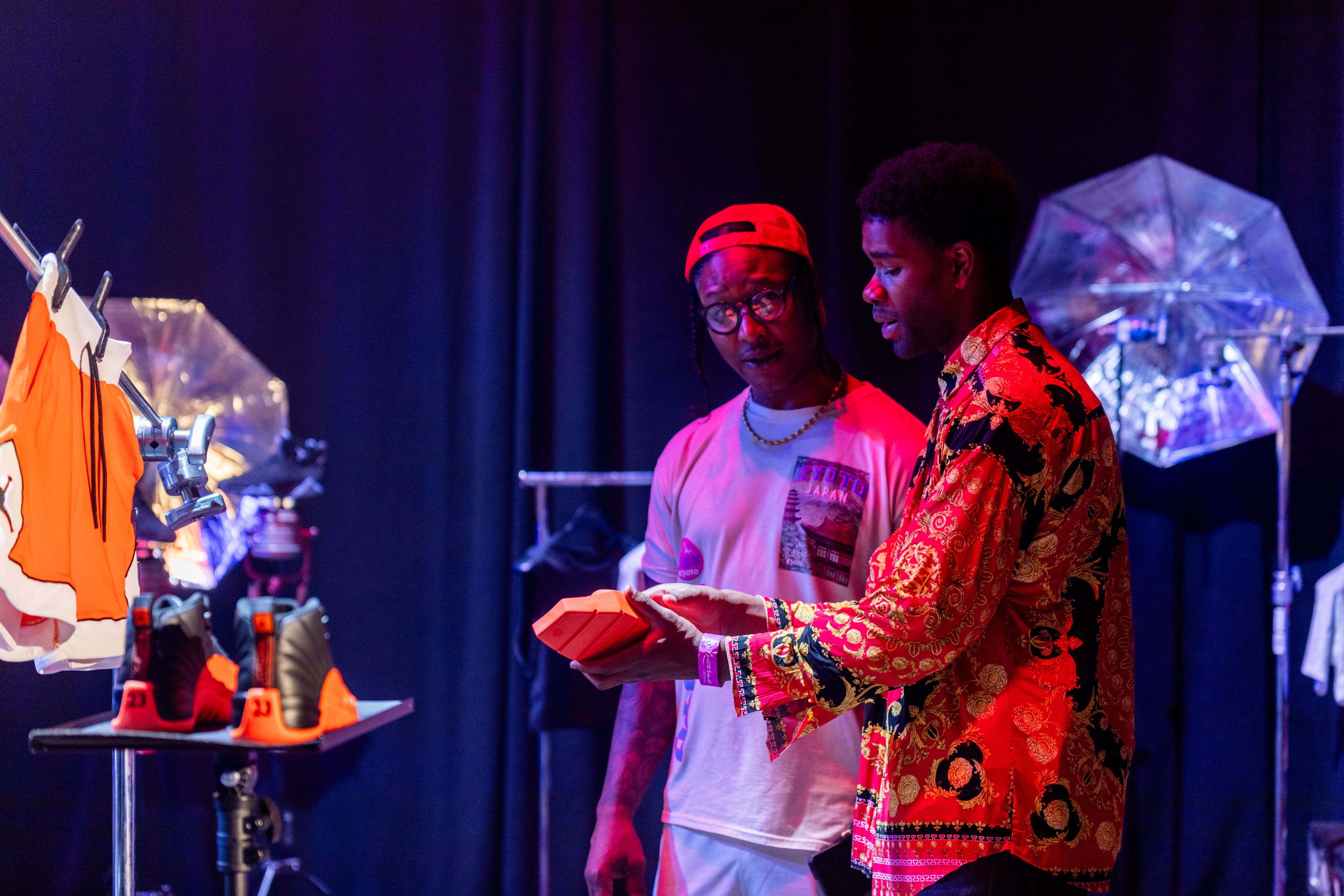Nike Jordan Brand WNBA All-Star Weekend Las Vegas male holding a bright orange jordan sneaker while other male listens to him