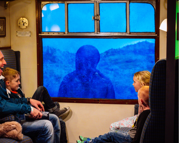 image of family on train looking out of their window at a shadowy figure