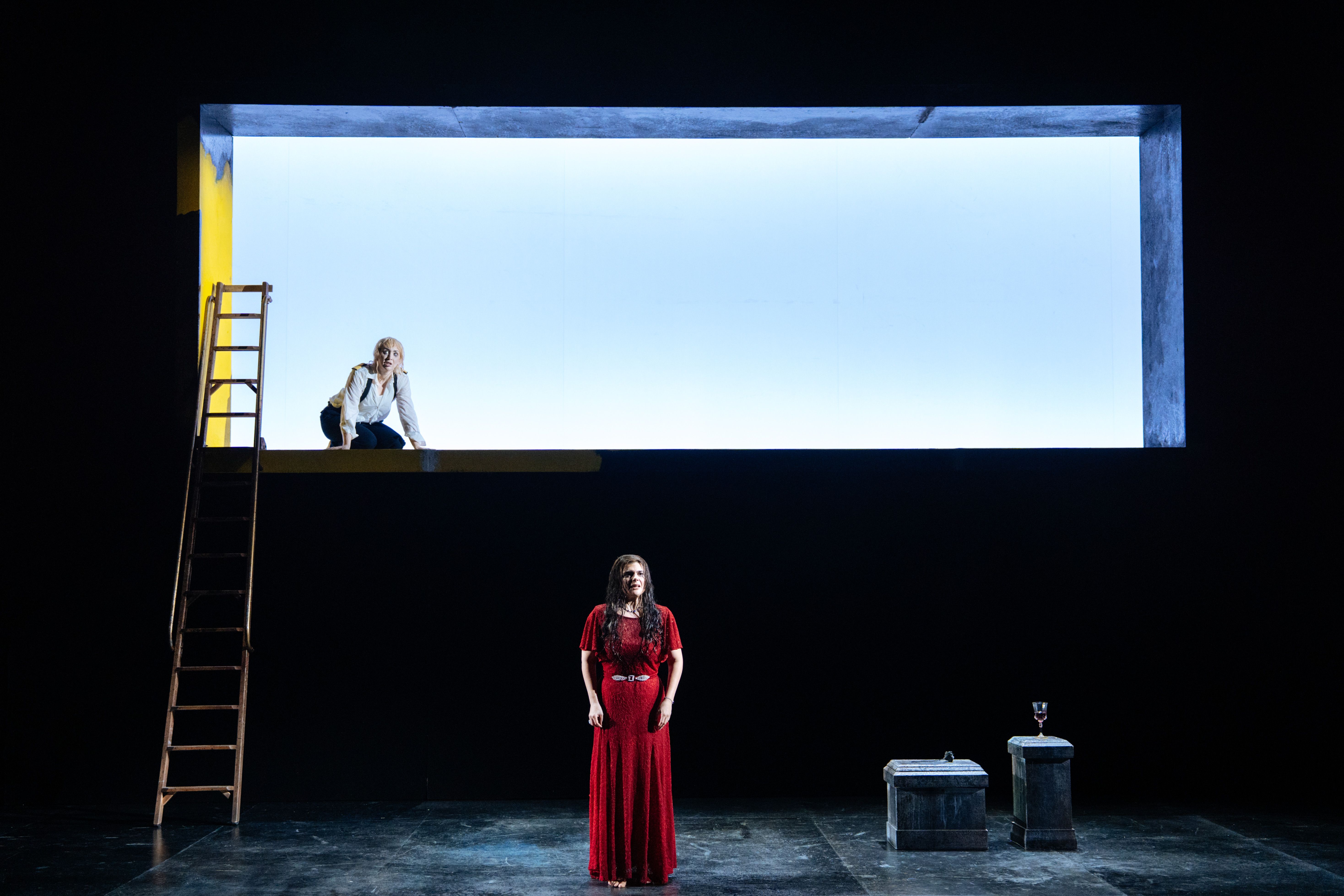 2 performers on stage with backlighting and stepladders with minimal props