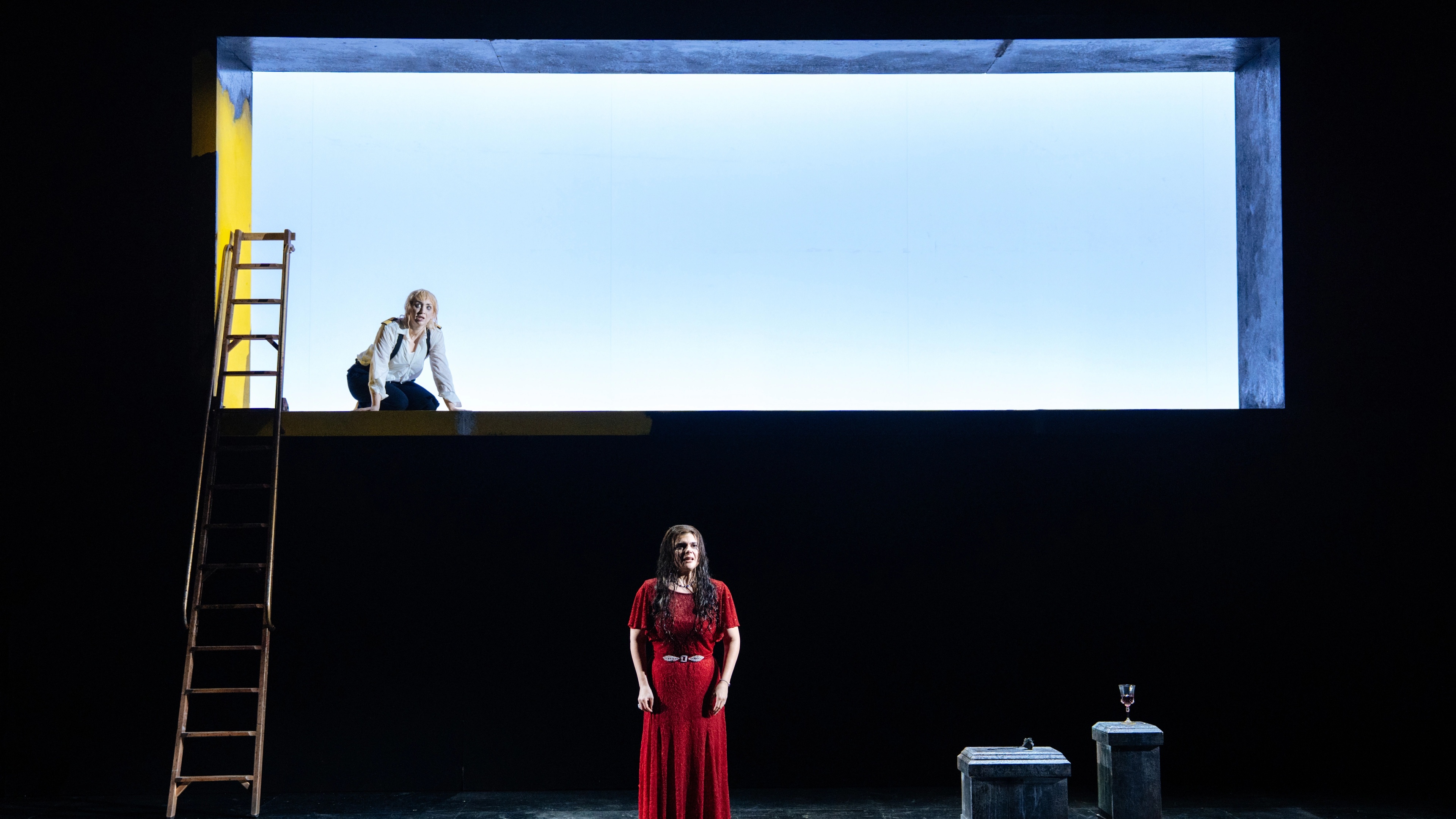 2 performers on stage with backlighting and stepladders with minimal props