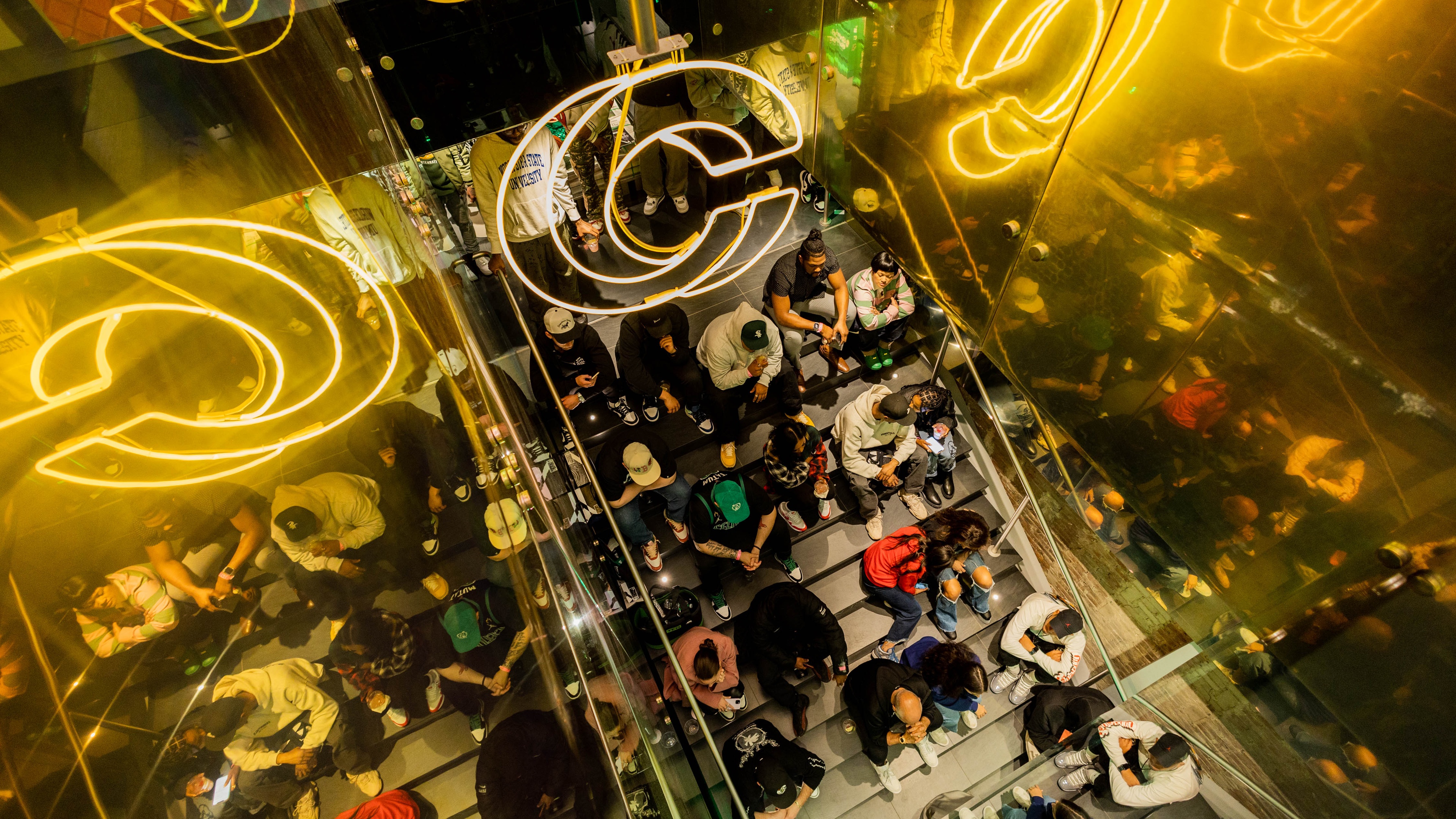 people sat on steps in a Nike brand experience with neon lettering and gold lighting with mirror