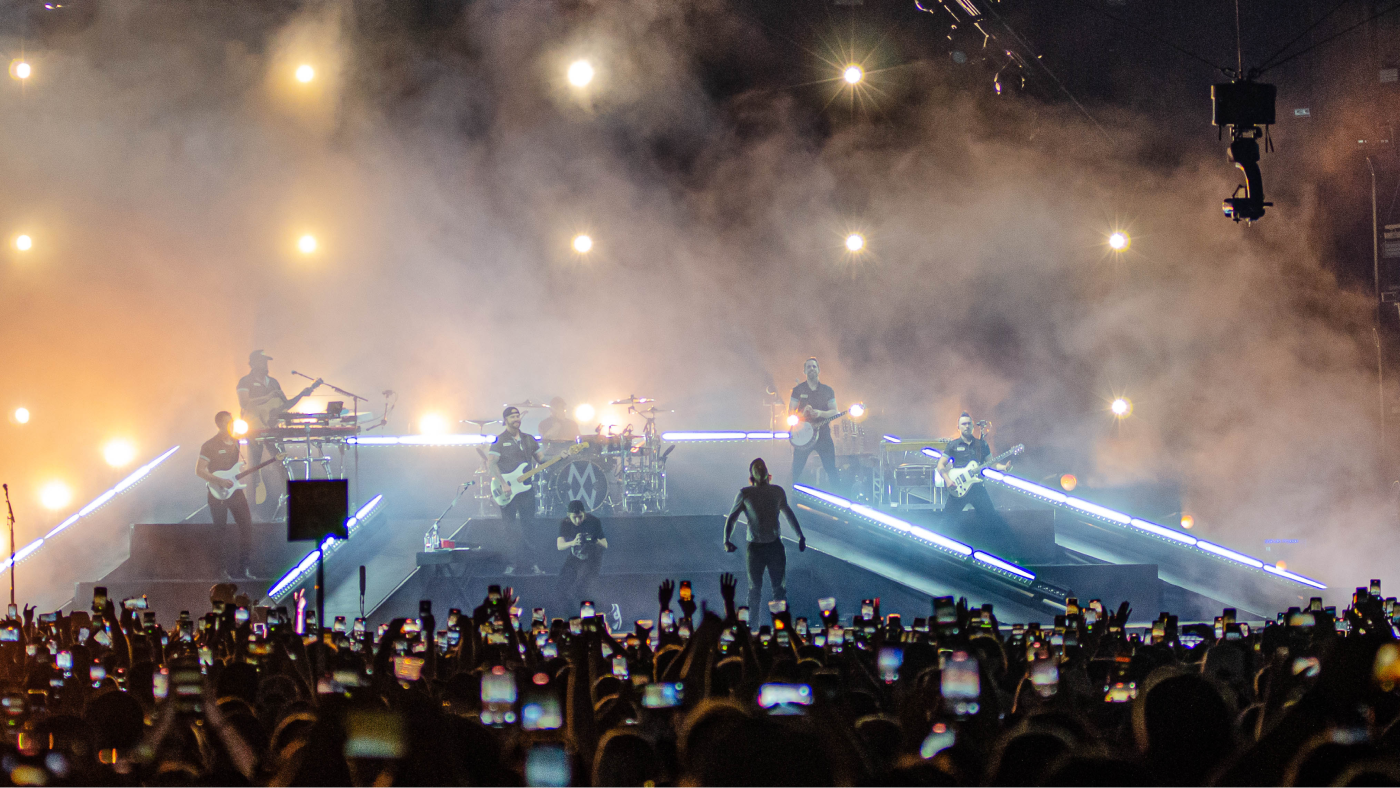 band performing from the audience perspective surrounded by stage fog