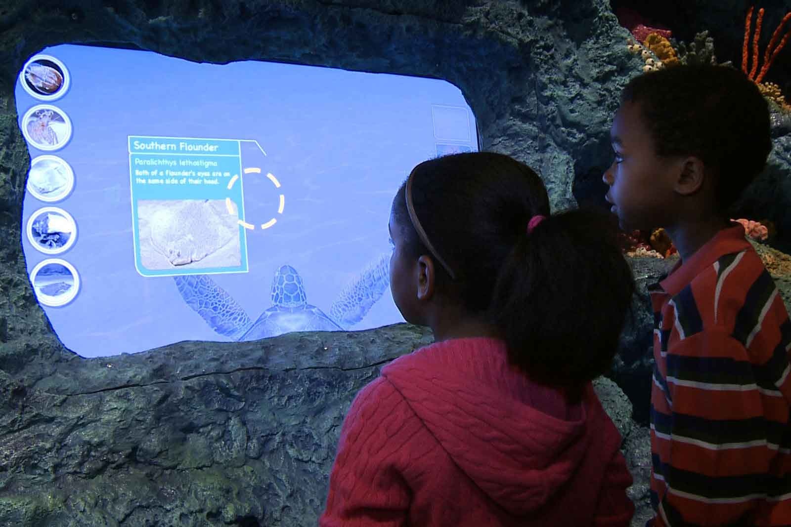 Two children interacting with LED display on rock