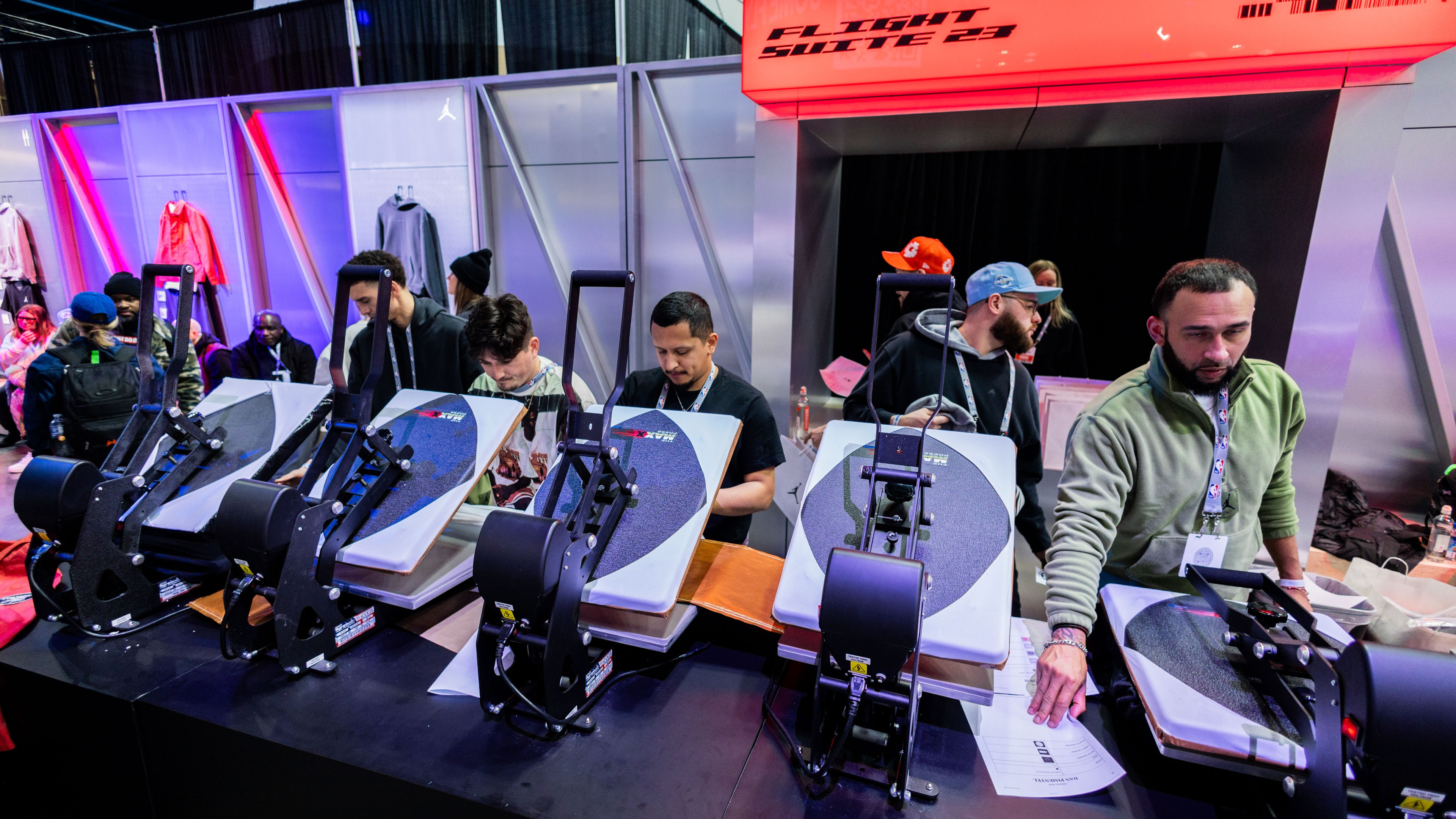 Group of people using heat press to personalise sports jersey at brand activation