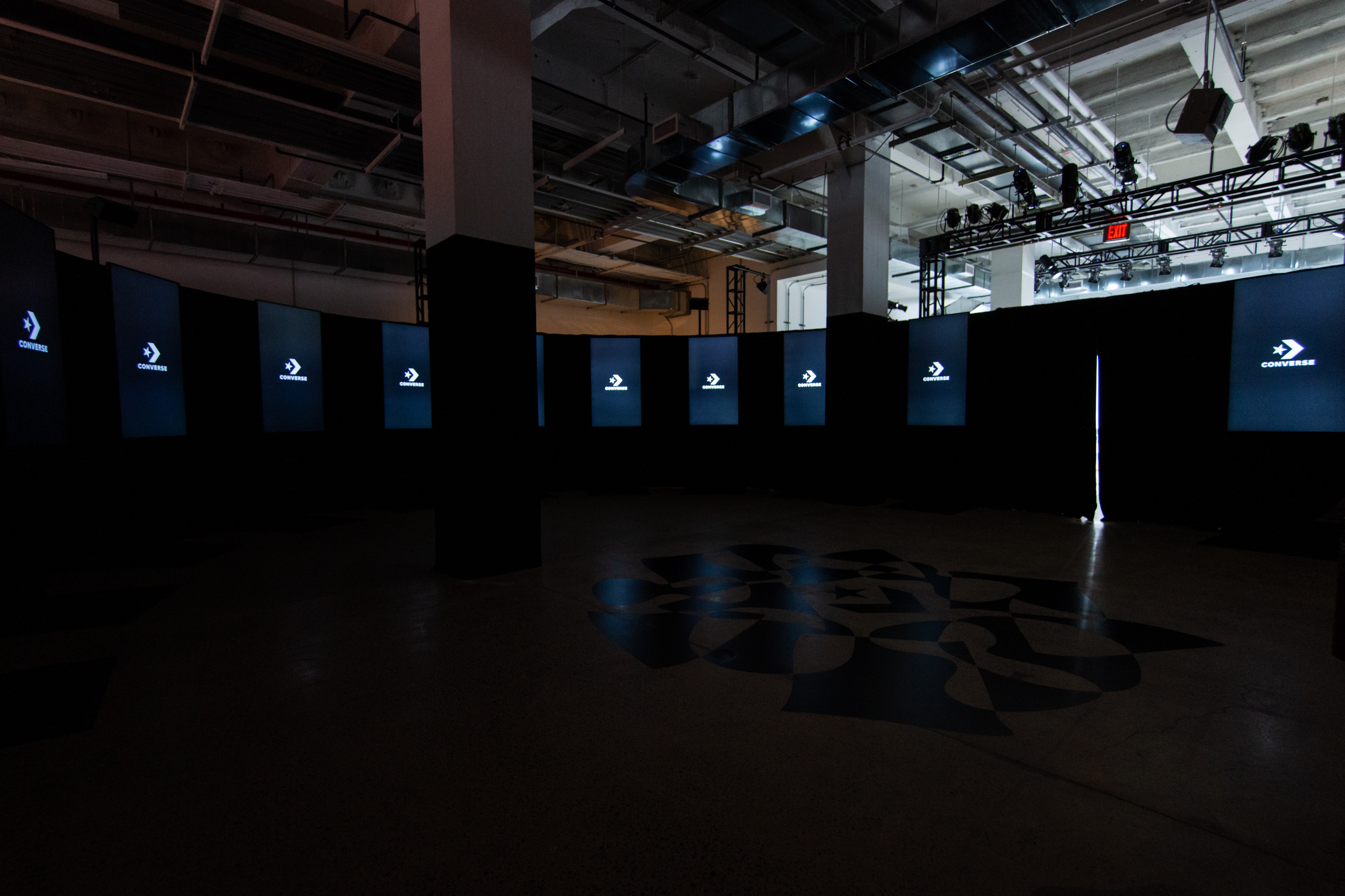 Circular room with black video screens with Converse logo on it