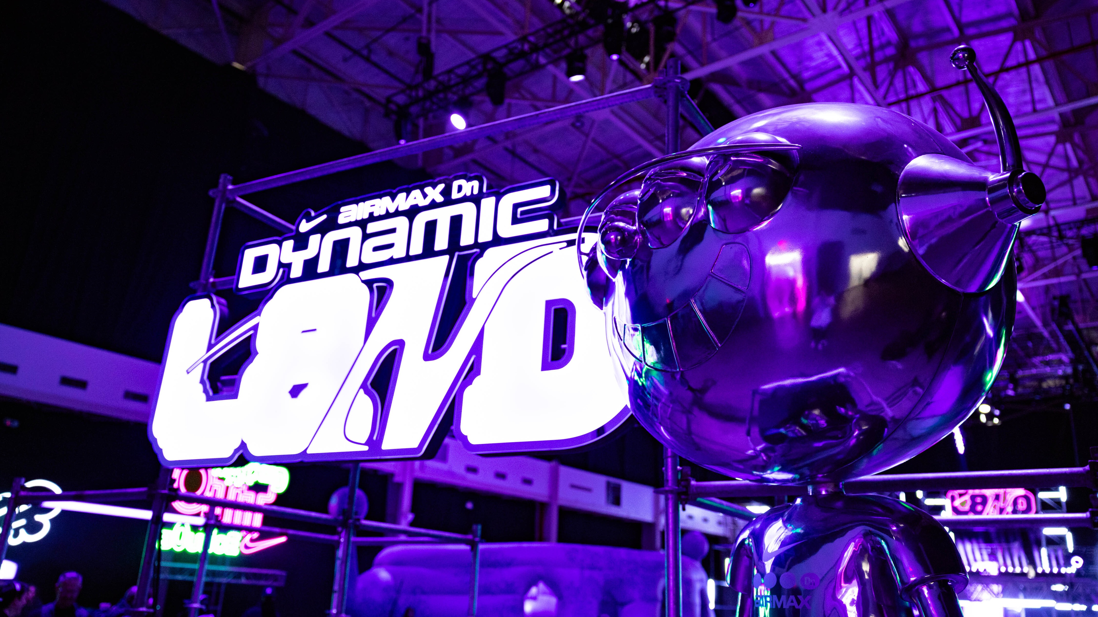 Large robot sculpture with Dynamic Land neon words beside it