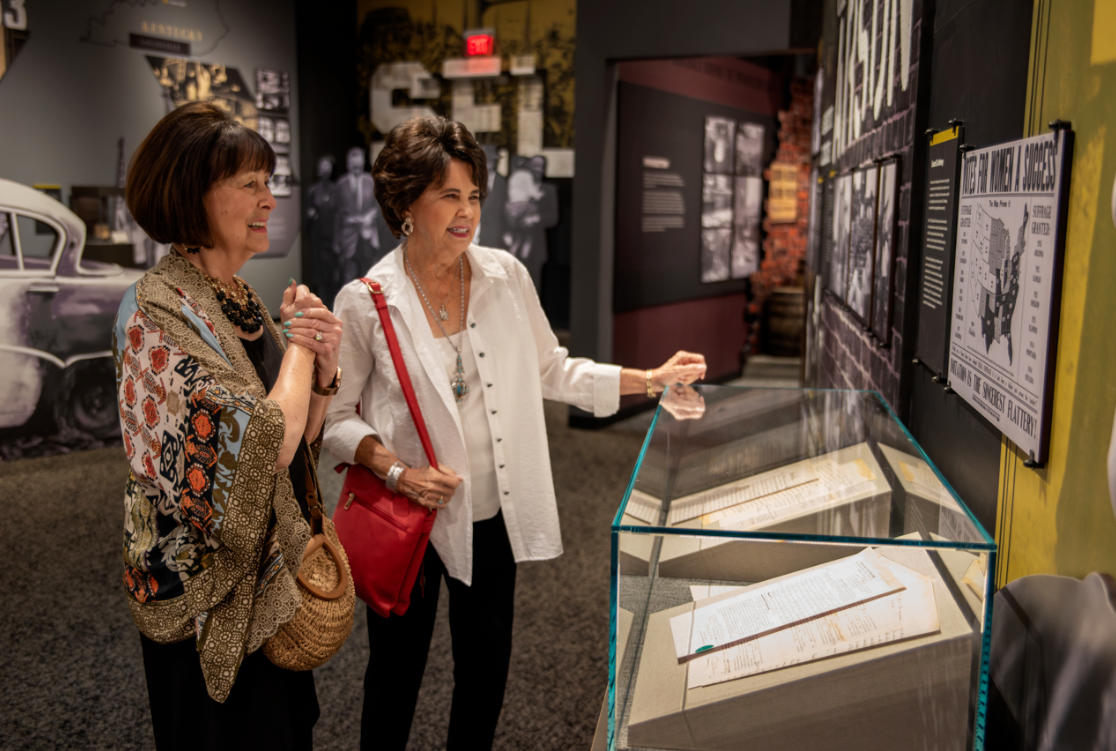 Two museum-goers enjoying a glass box display of historic items