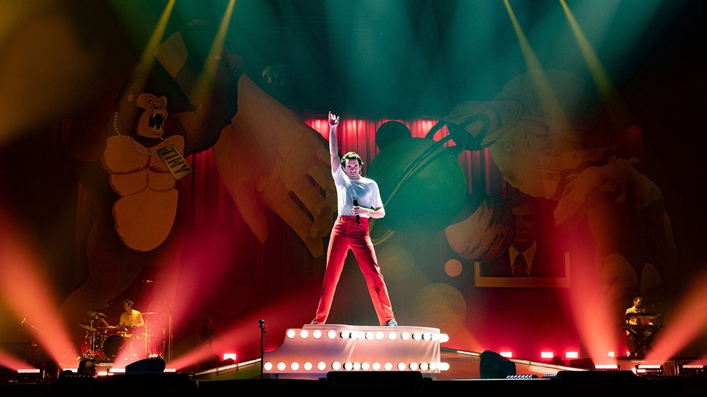 Man on stage with arm up and singing