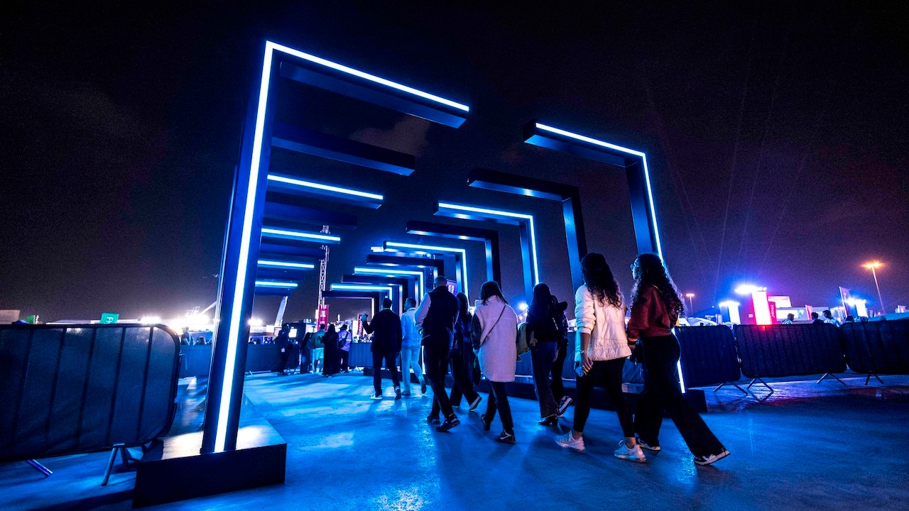 Concert attendees walking through blue LED walkway at night