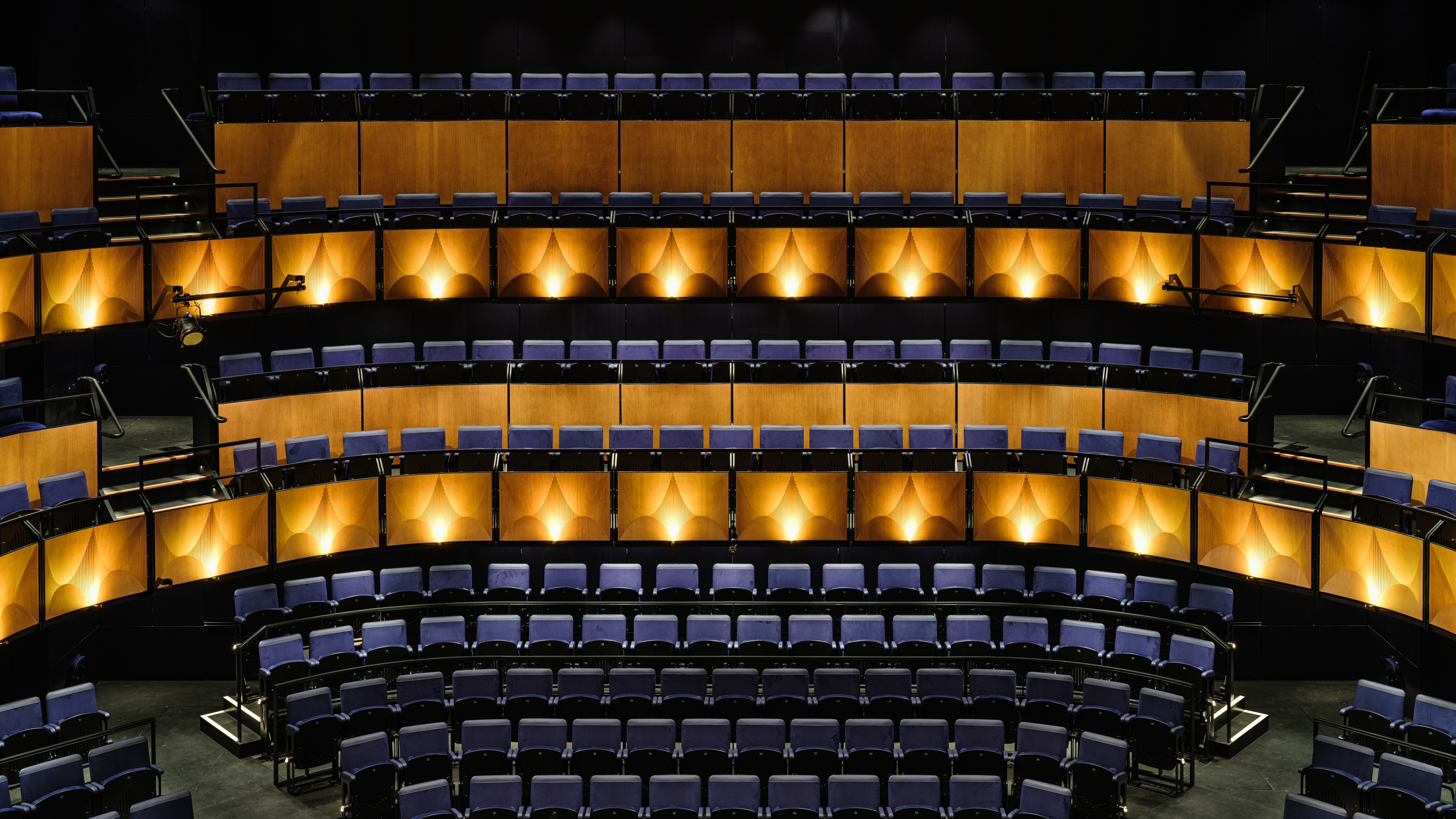 Interior of @sohoplace theatre with navy blue seats and warm yellow lighting