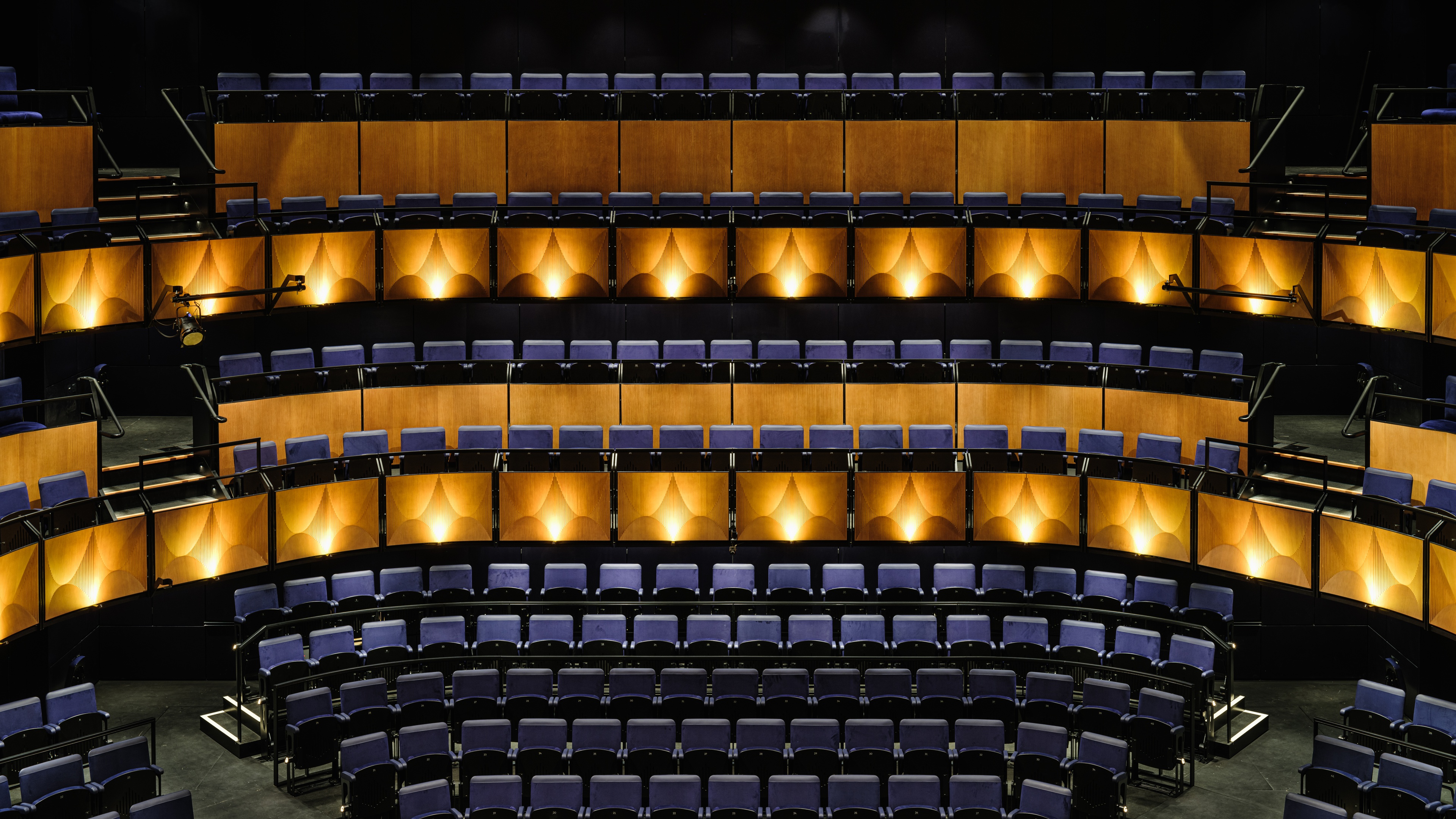 Interior of @sohoplace theatre with navy blue seats and warm yellow lighting