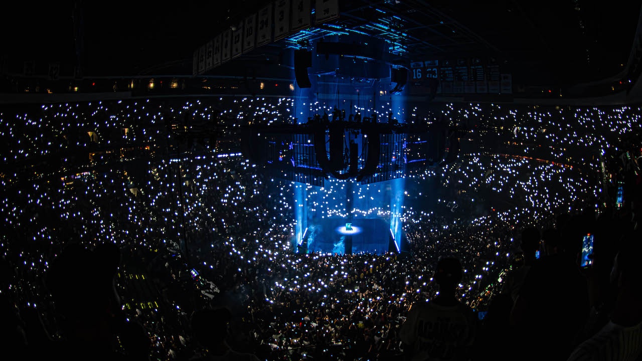 Arena live experience stage lit blue with hundreds of phone lights