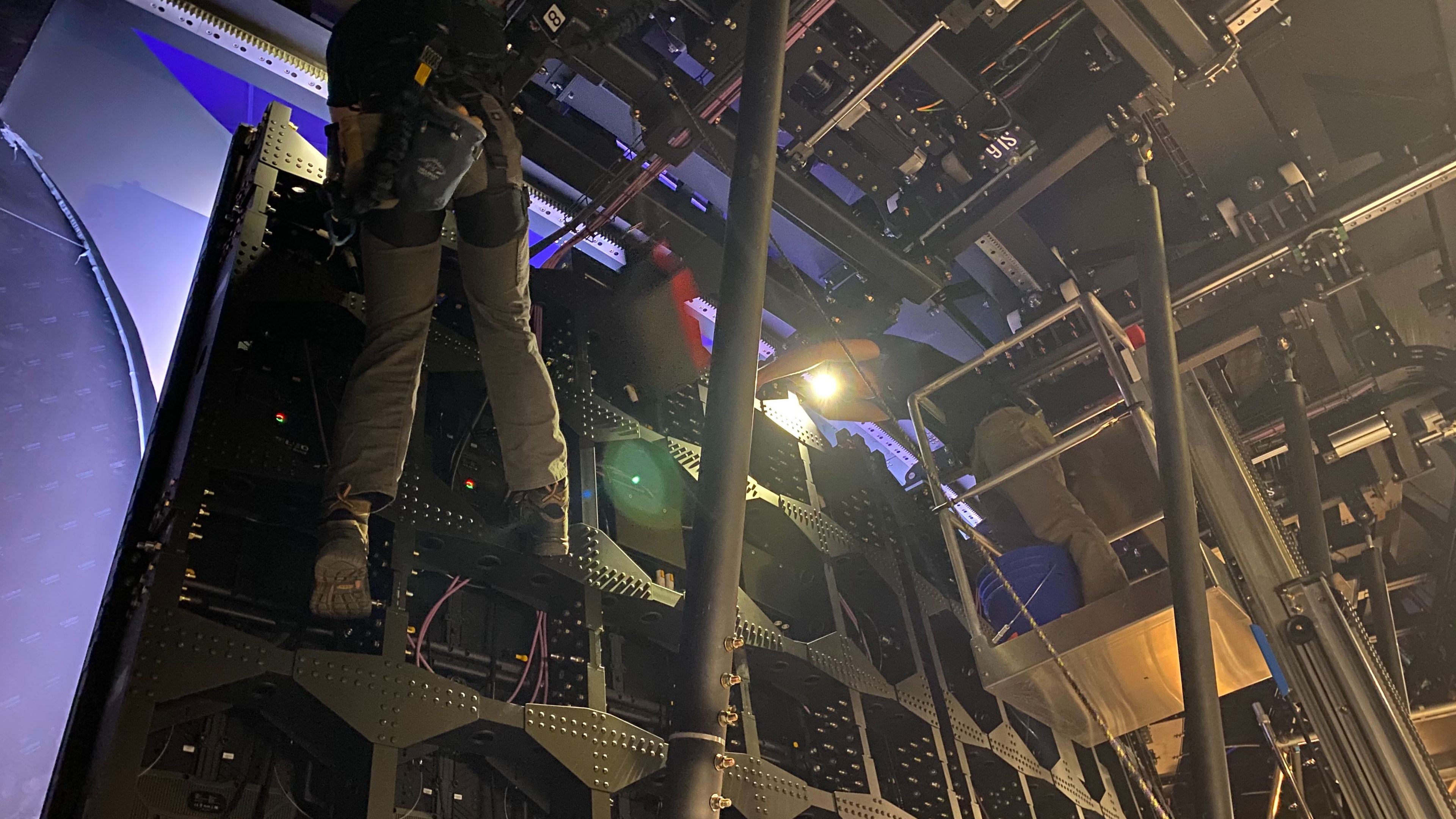 Person wearing harness scaling the back of LED screen