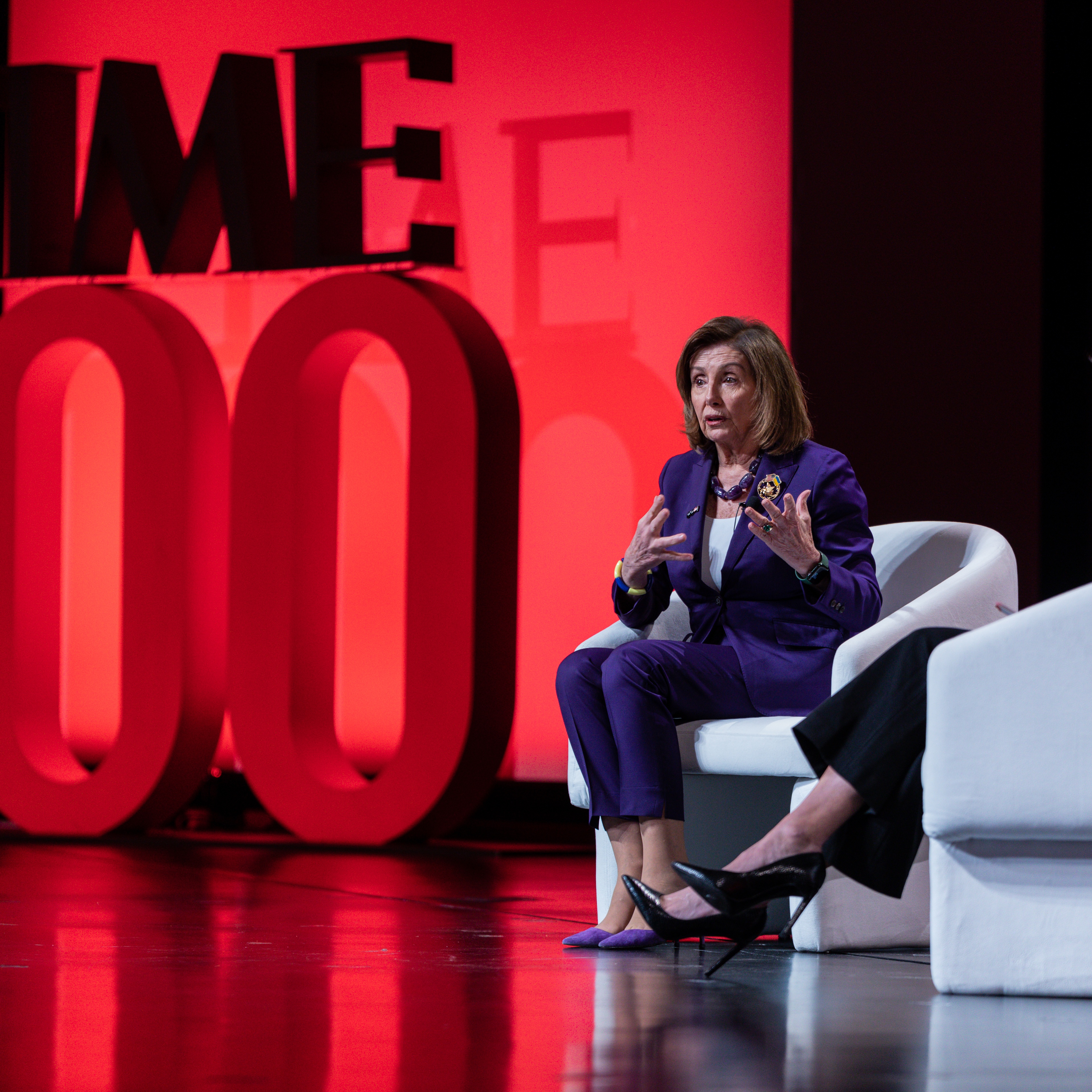 Two people on chairs with TIME100 in large scenic lettering