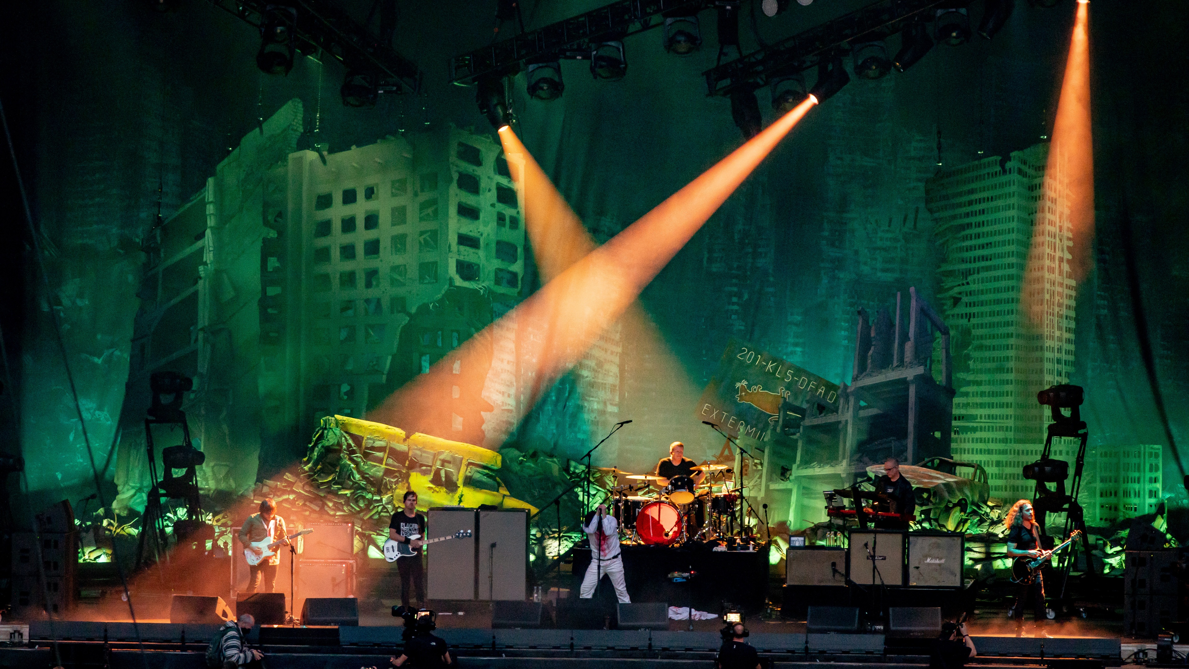 My Chemical Romance on stage performing during the Foundations Tour in a destroyed city backdrop lit up in green tones