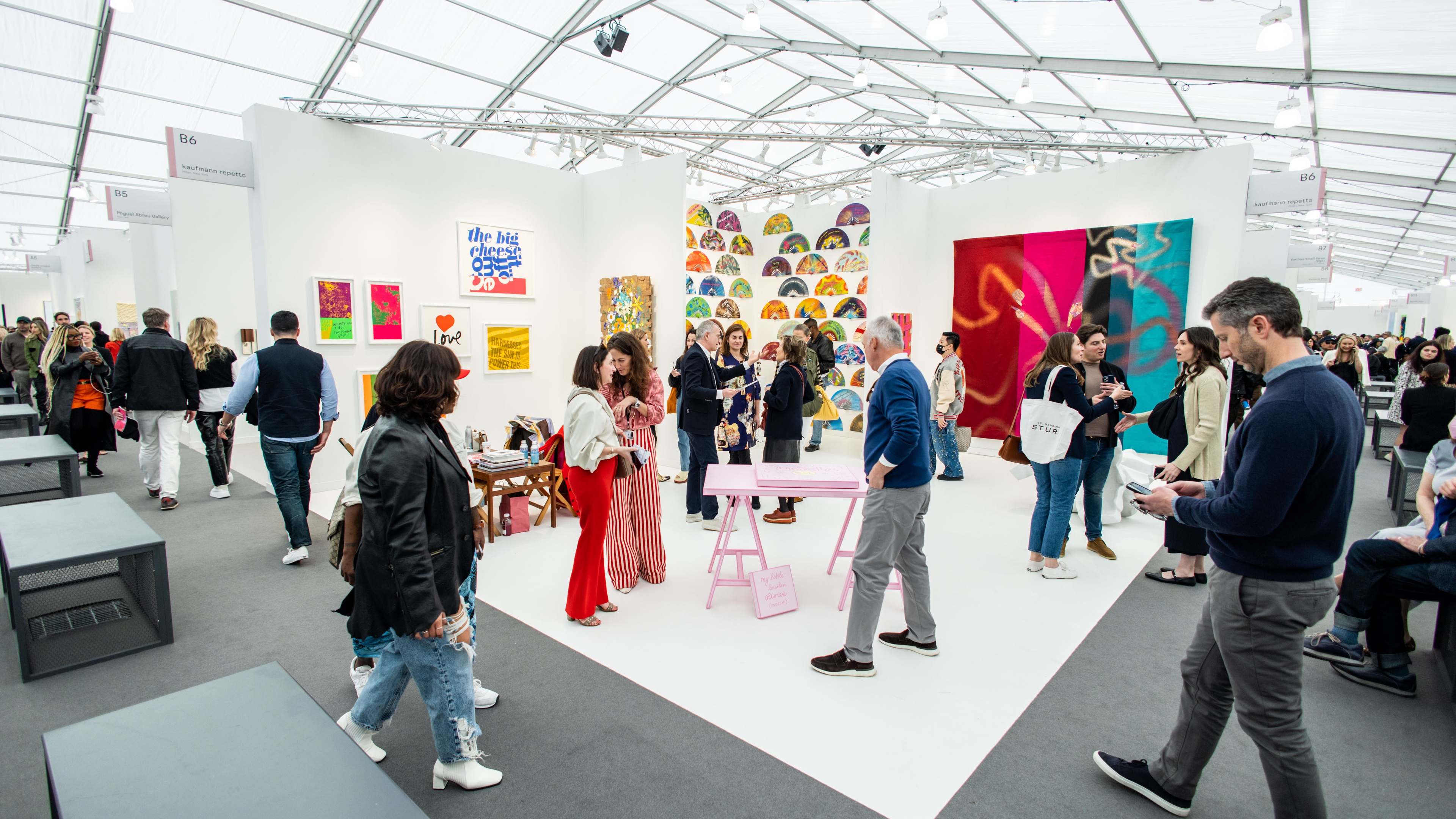 People looking at art in a gallery inside a large white tent
