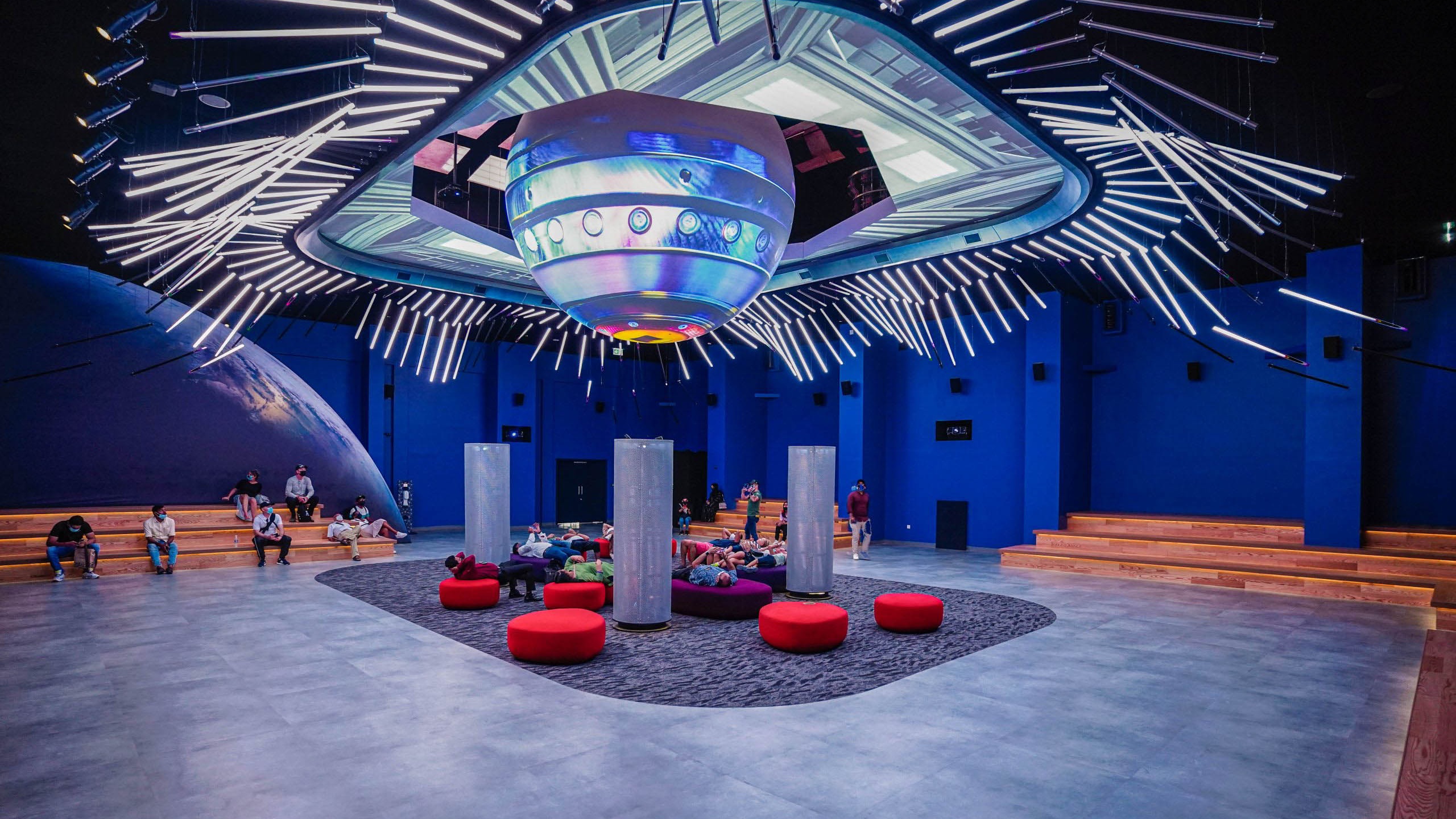 Large sphere with projection content over a seating area with red seats