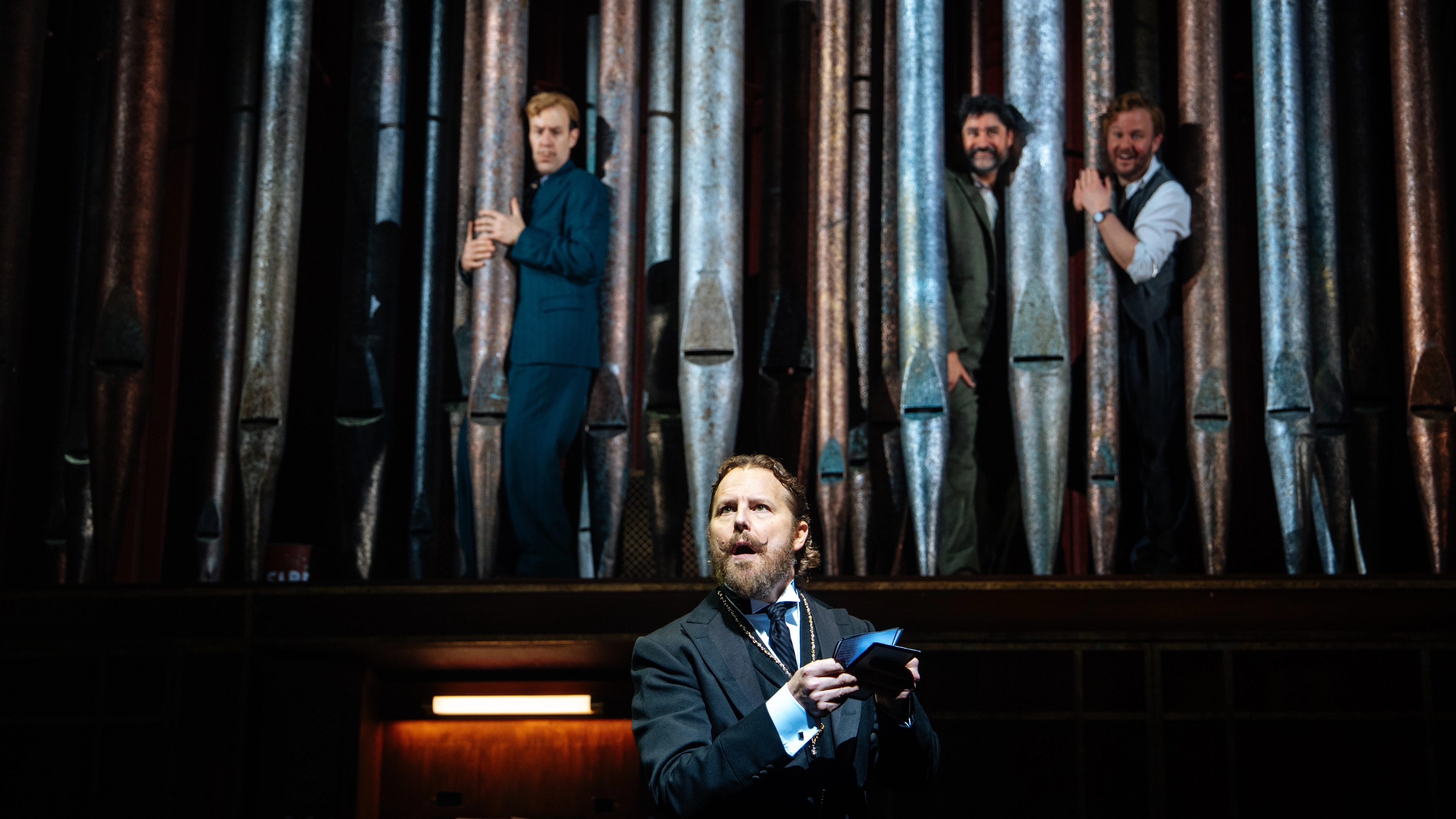 performers looking out to audience in front of large pipes and piano