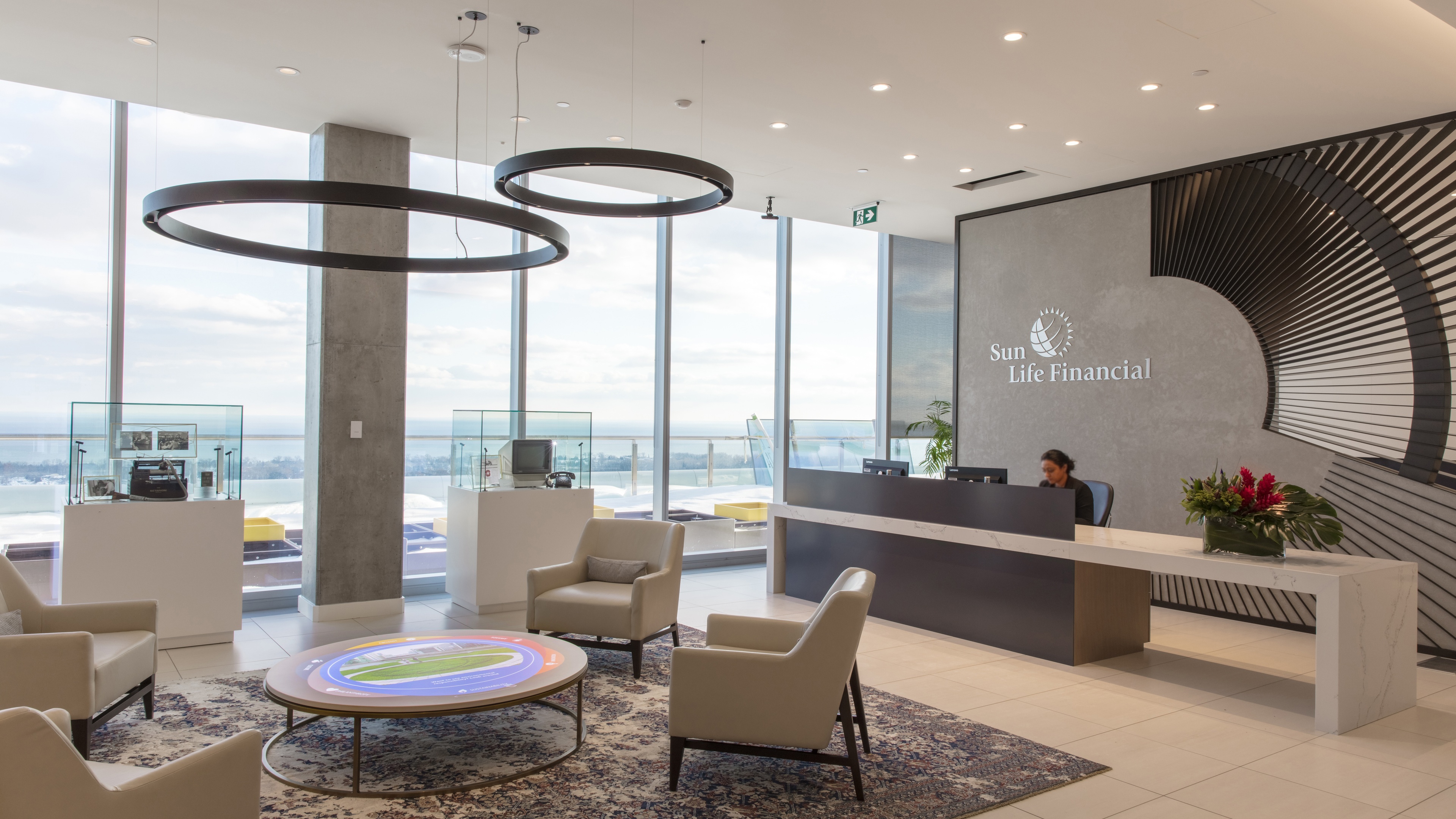 Wide shot of corporate entrance with large windows overlooking skyline