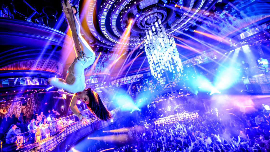 club full of people dancing with trapeze artist hanging in midair