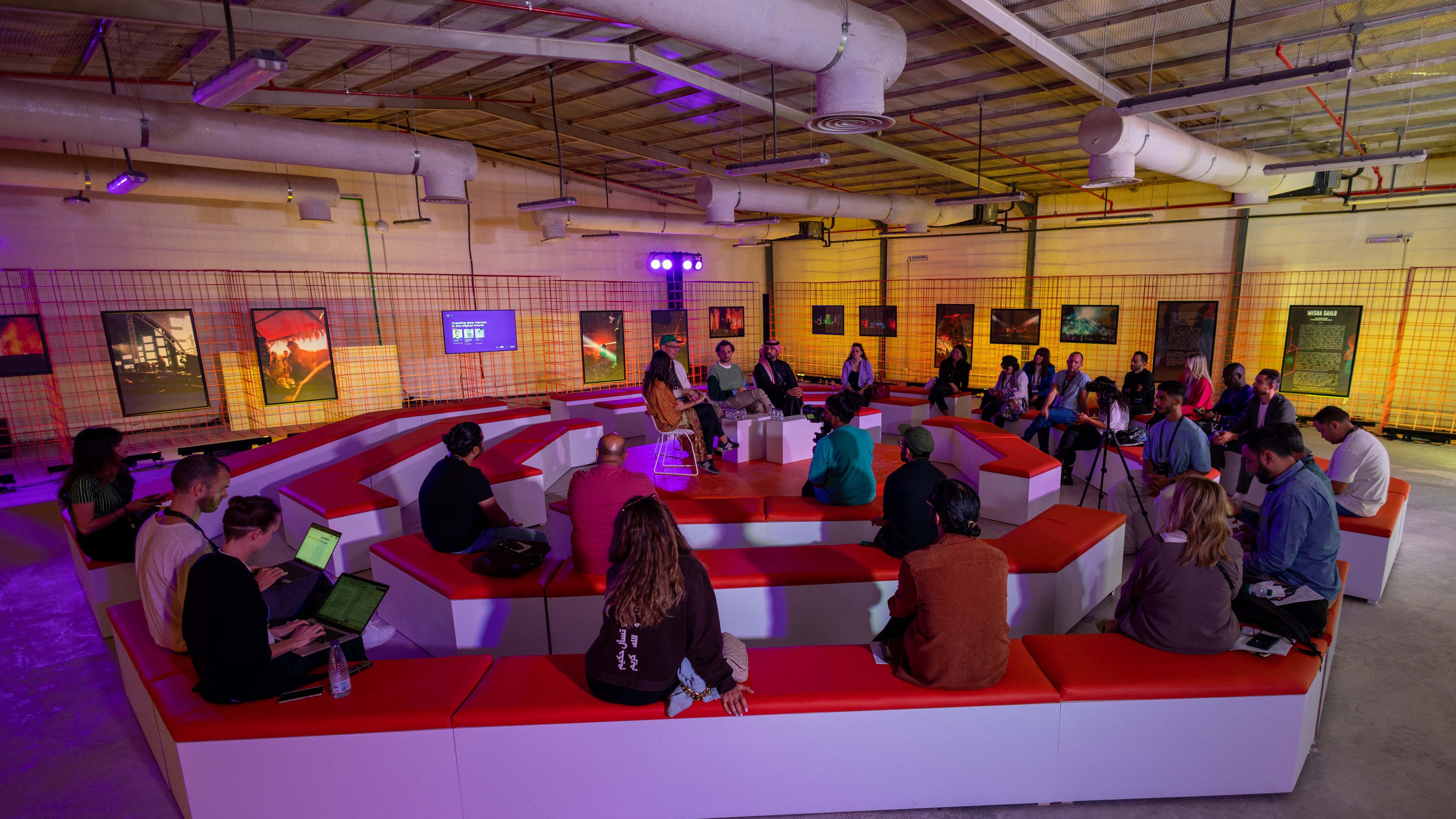 Conference attendees sit in a circular pattern in an industrial style room