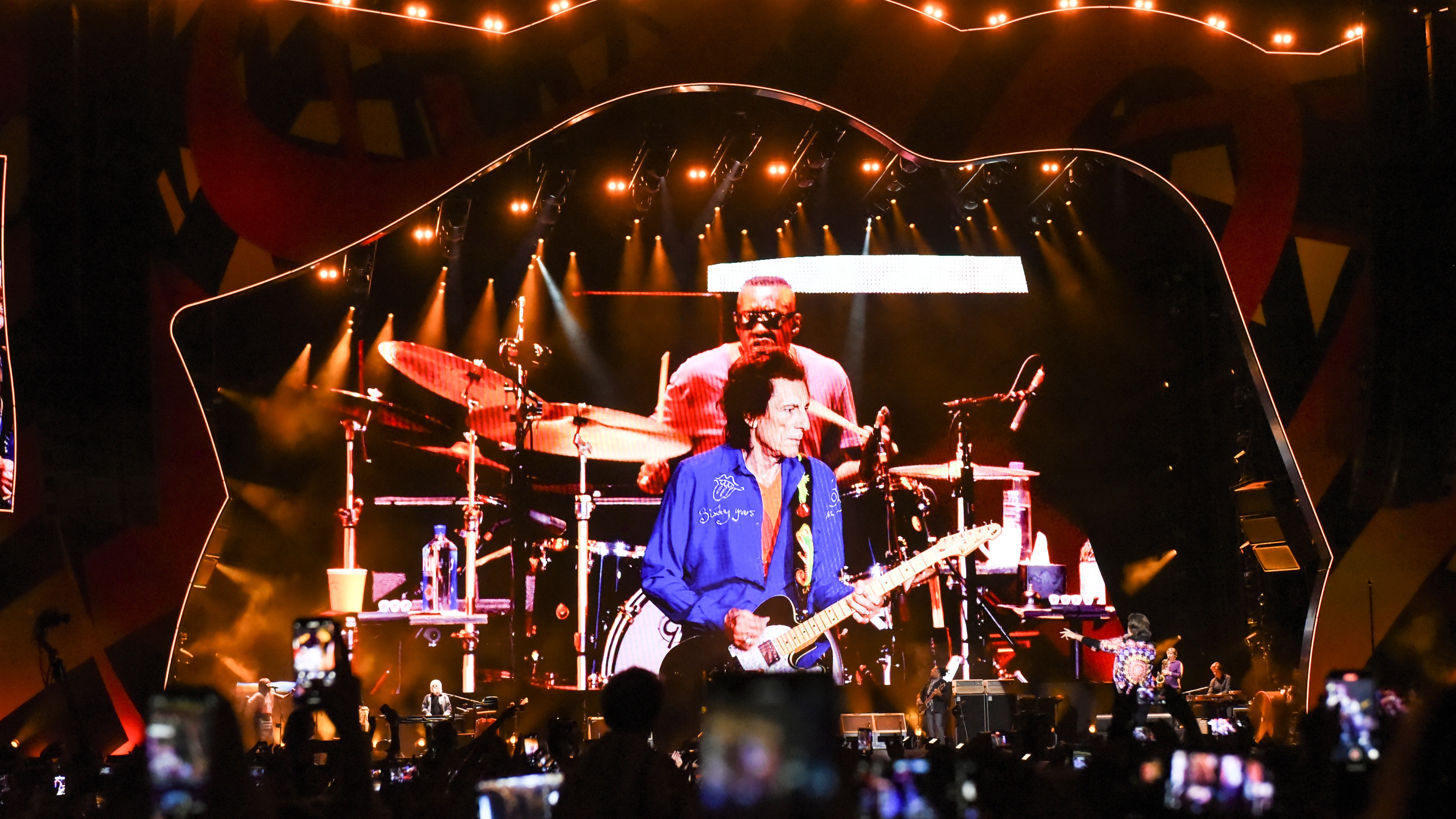 The Rolling Stones performing on stage in front of crowd with LED screen showing Steve Jordan on the drums