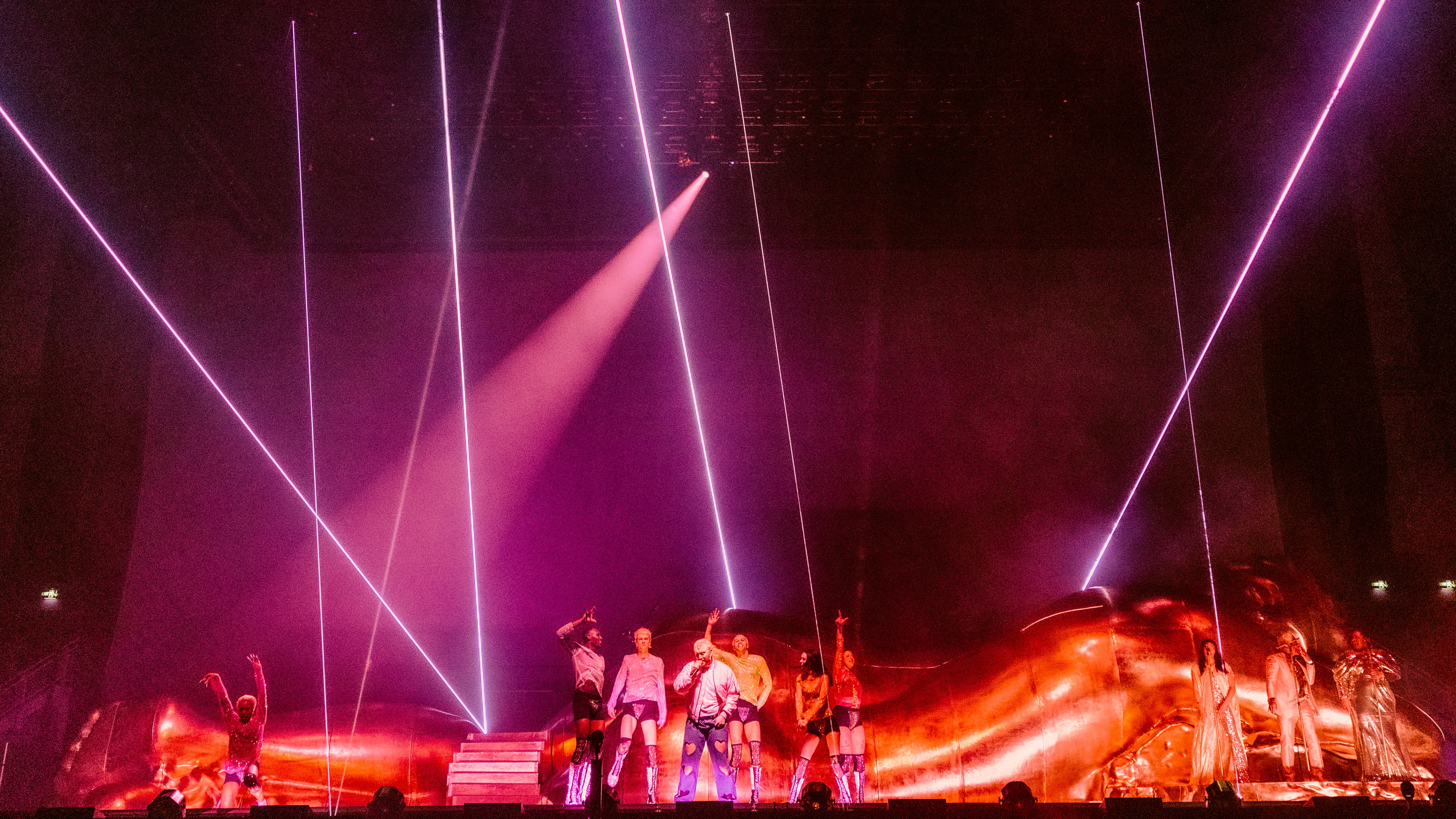 Sam Smith on stage in front of Gloria sculpture with purple lasers