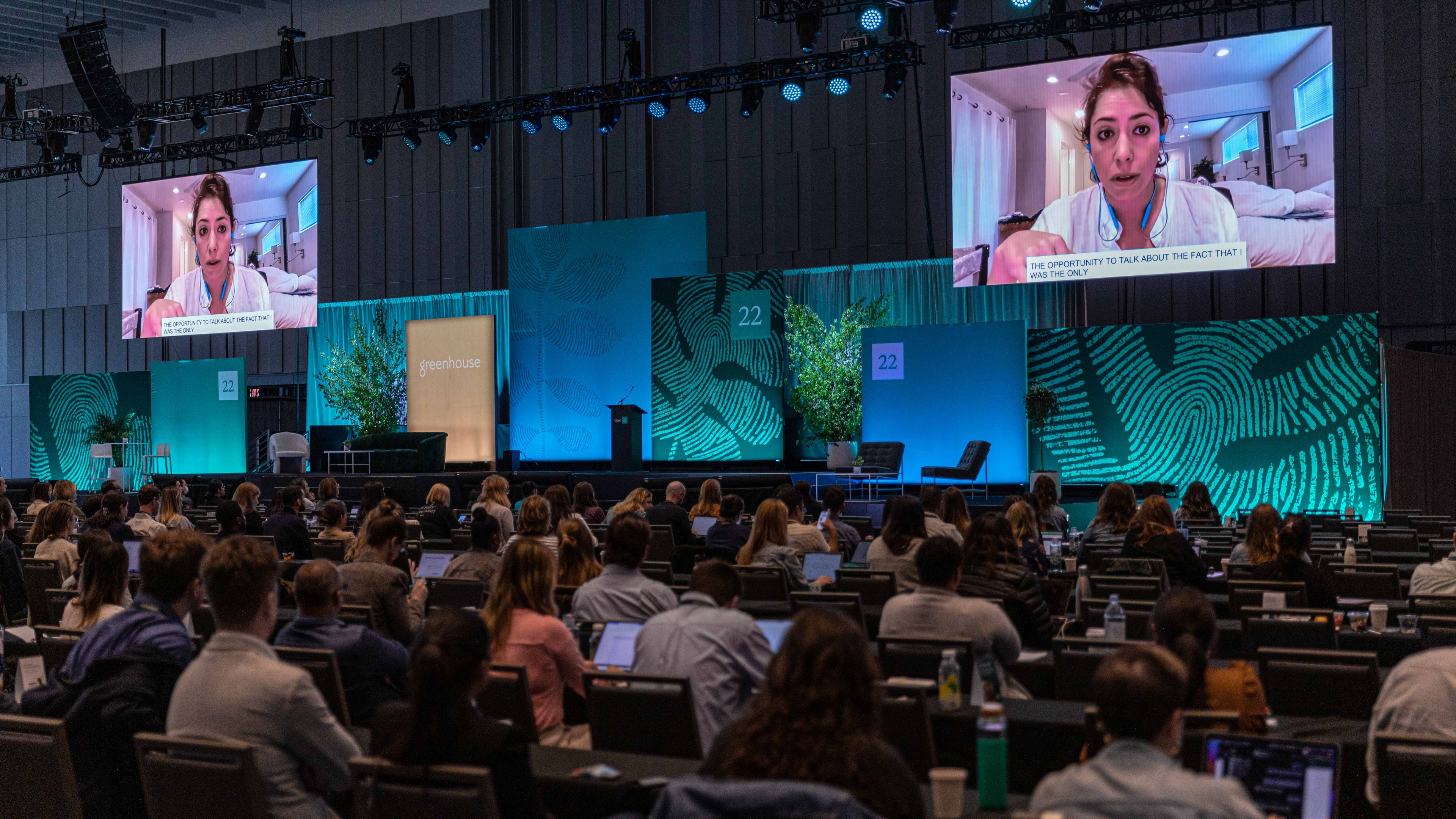 People watching conference with speaker on large screens